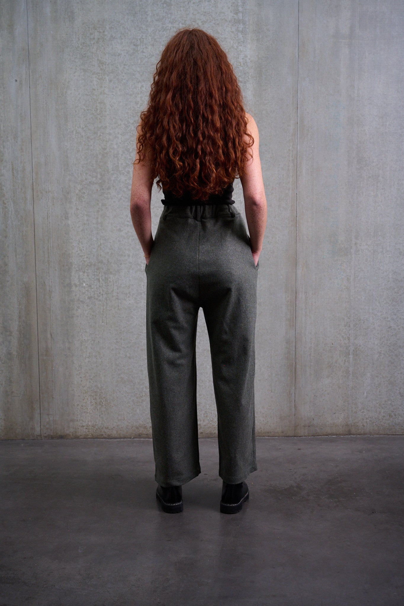 Pantalon droit de la marque Aïdama, coupe large en flanelle de laine grise. Porté par une mannequin femme et vue de dos.