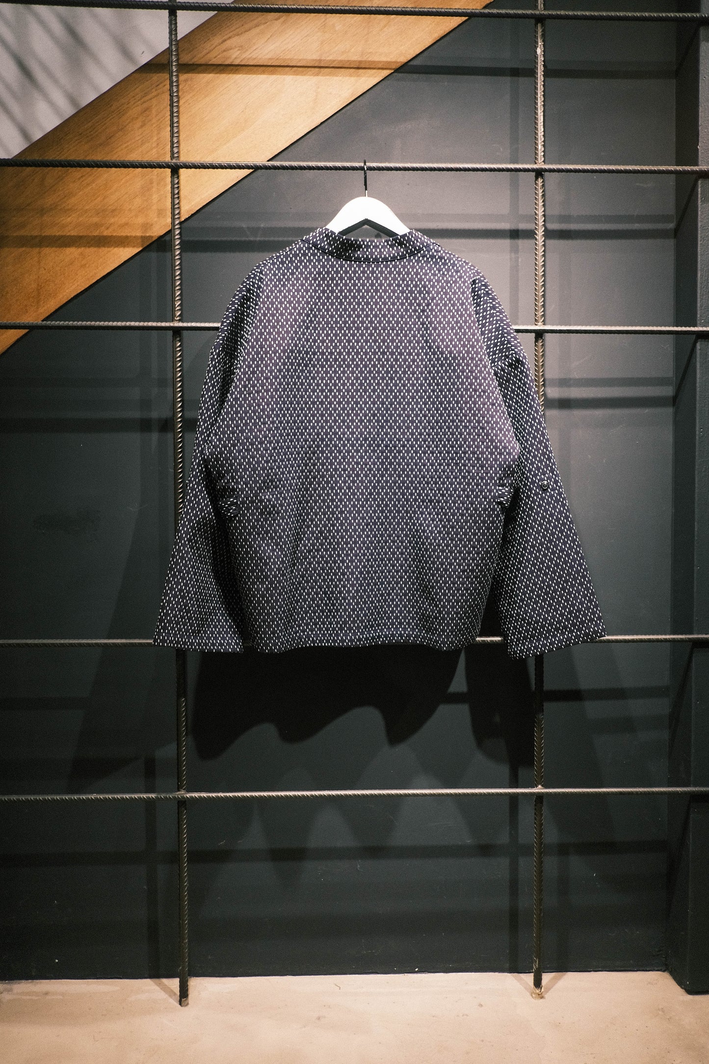 Veste croisée à col kimono de la marque Aïdama, modèle Samue en coton japonais bleu brodé de points Sashiko. Vue de dos sur ceintre.