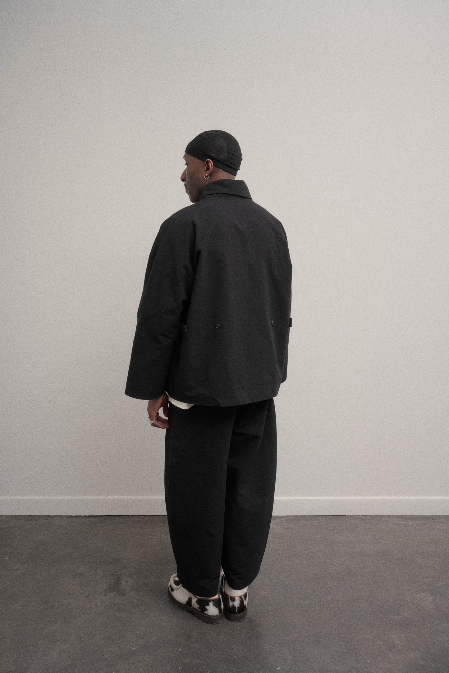 Veste oversize à col arrondi de la marque Aïdama en mélange de coton et papier japonais noir. Portée ouverte par un mannequin homme et vu de dos.