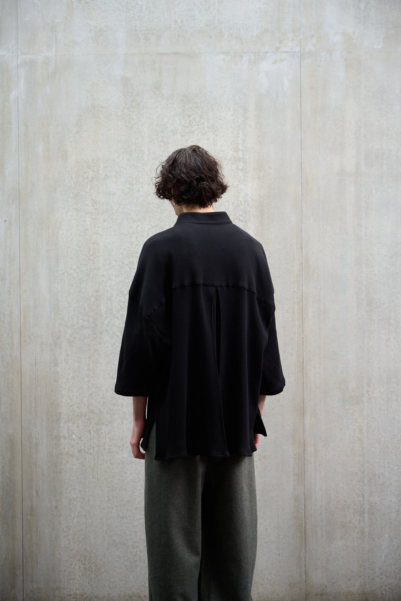 Chemise oversize à col officier, coupe boxy en coton nid d'abeille noir. Portée fermée par un mannequin homme et vue de dos.