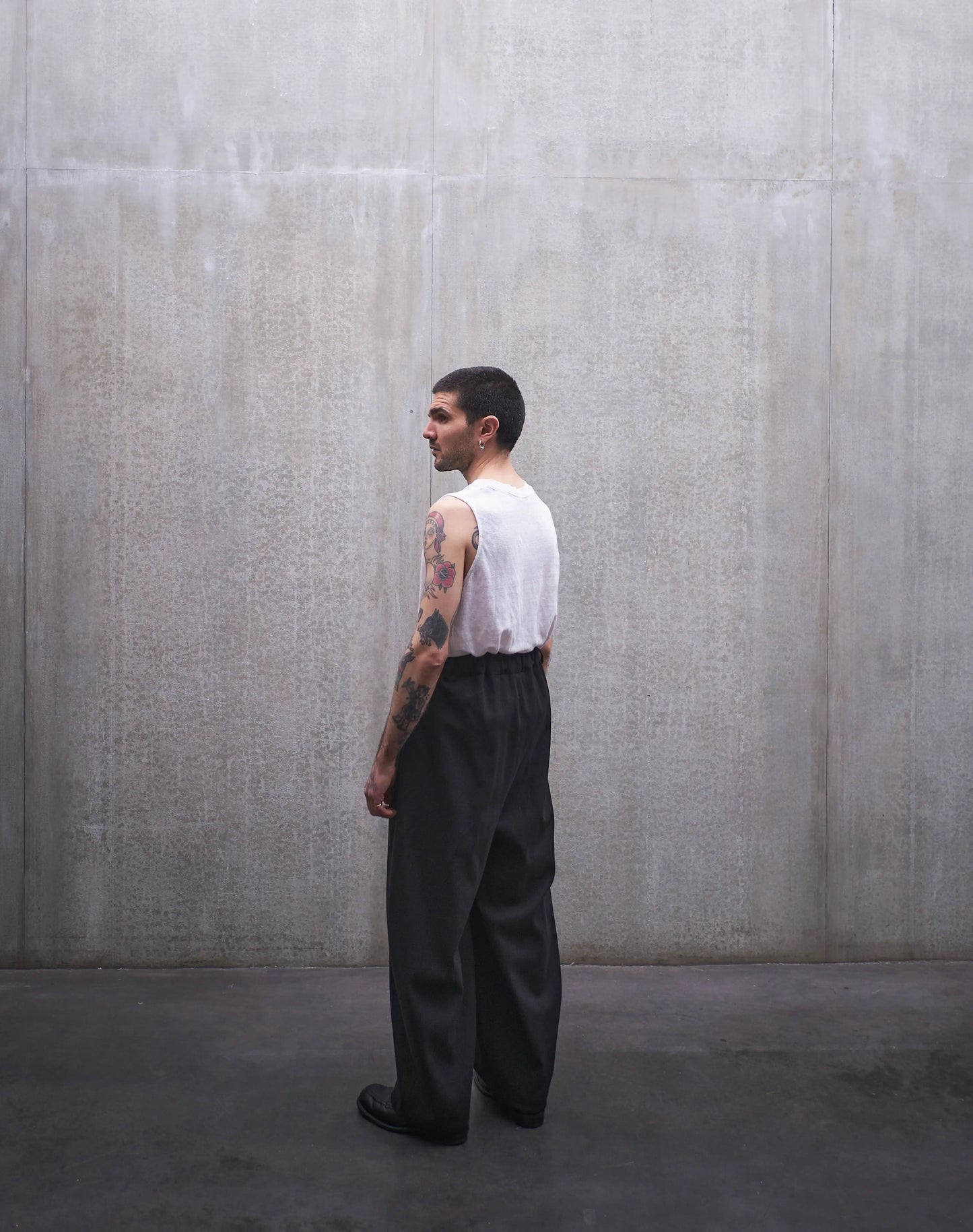 Pantalon circulaire Aïdama, coupe ballon en coton noir à motif Prince de Galles ton sur ton. Porté par un mannequin homme et vu de dos.