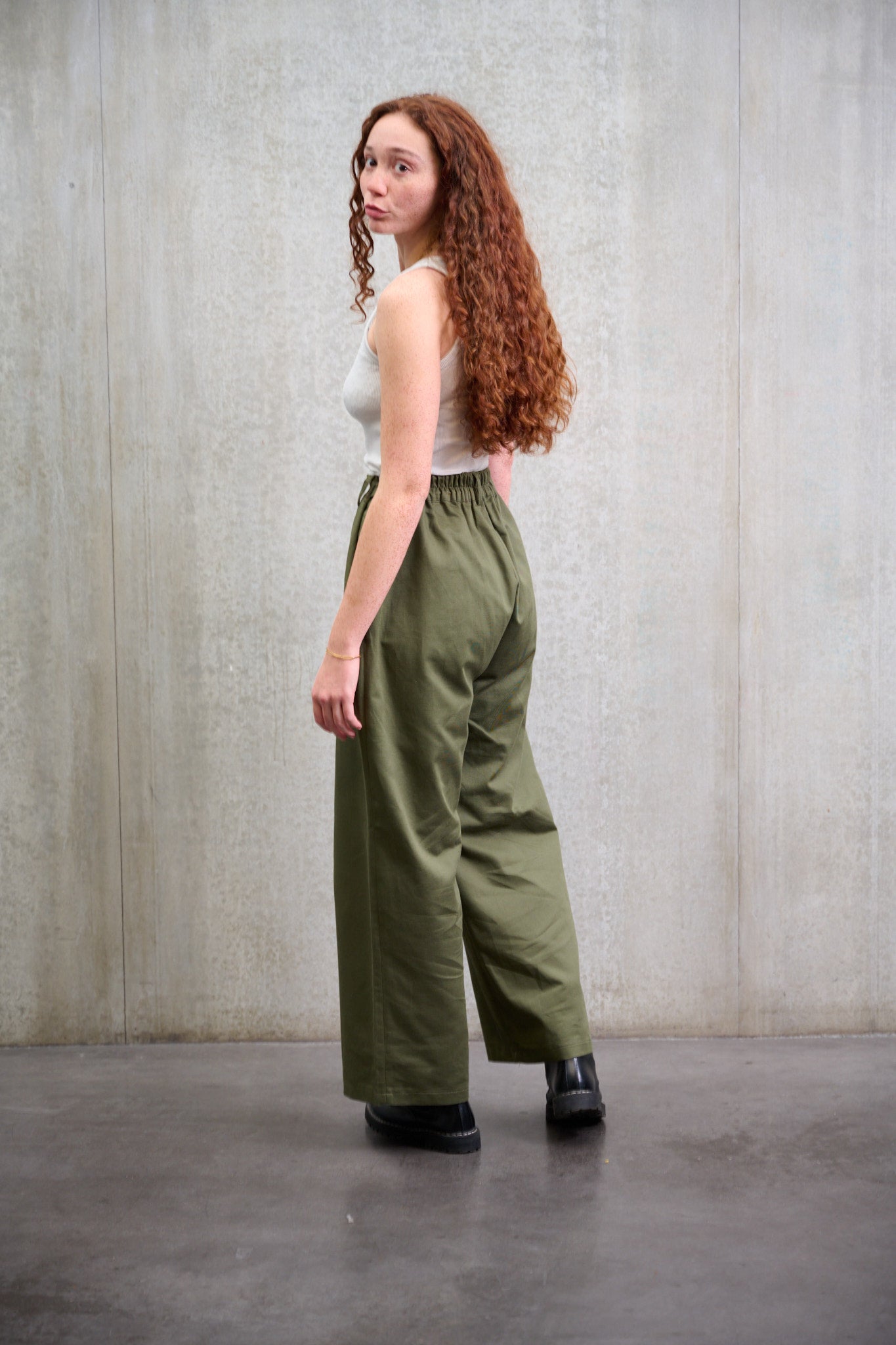 Pantalon droit à coupe ample en coton vert avec sangles de réglages de la marque Aïdama. Porté taille haute par une mannequin femme et vu de dos.