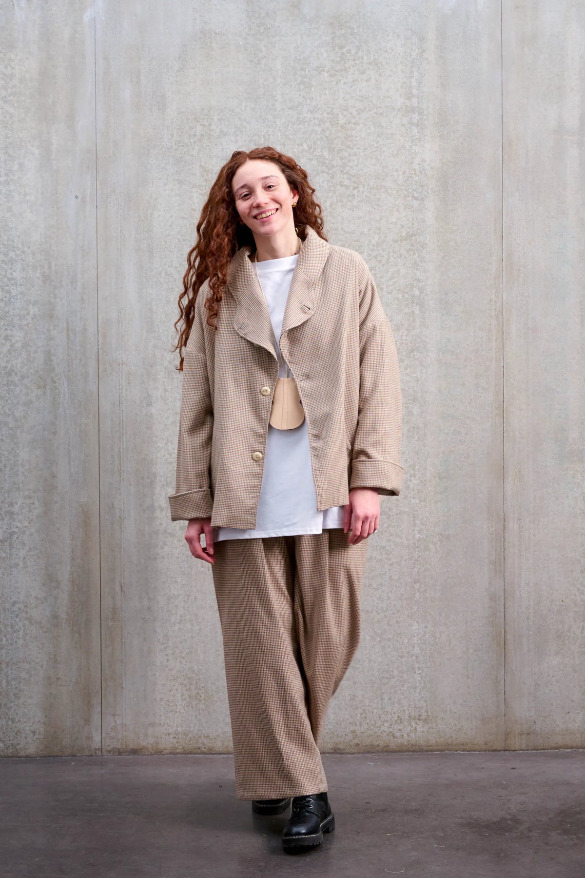 Pantalon droit de la marque Aïdama, coupe ample en laine marron à motif pied de poule. Porté par une mannequin femme et vu de face.