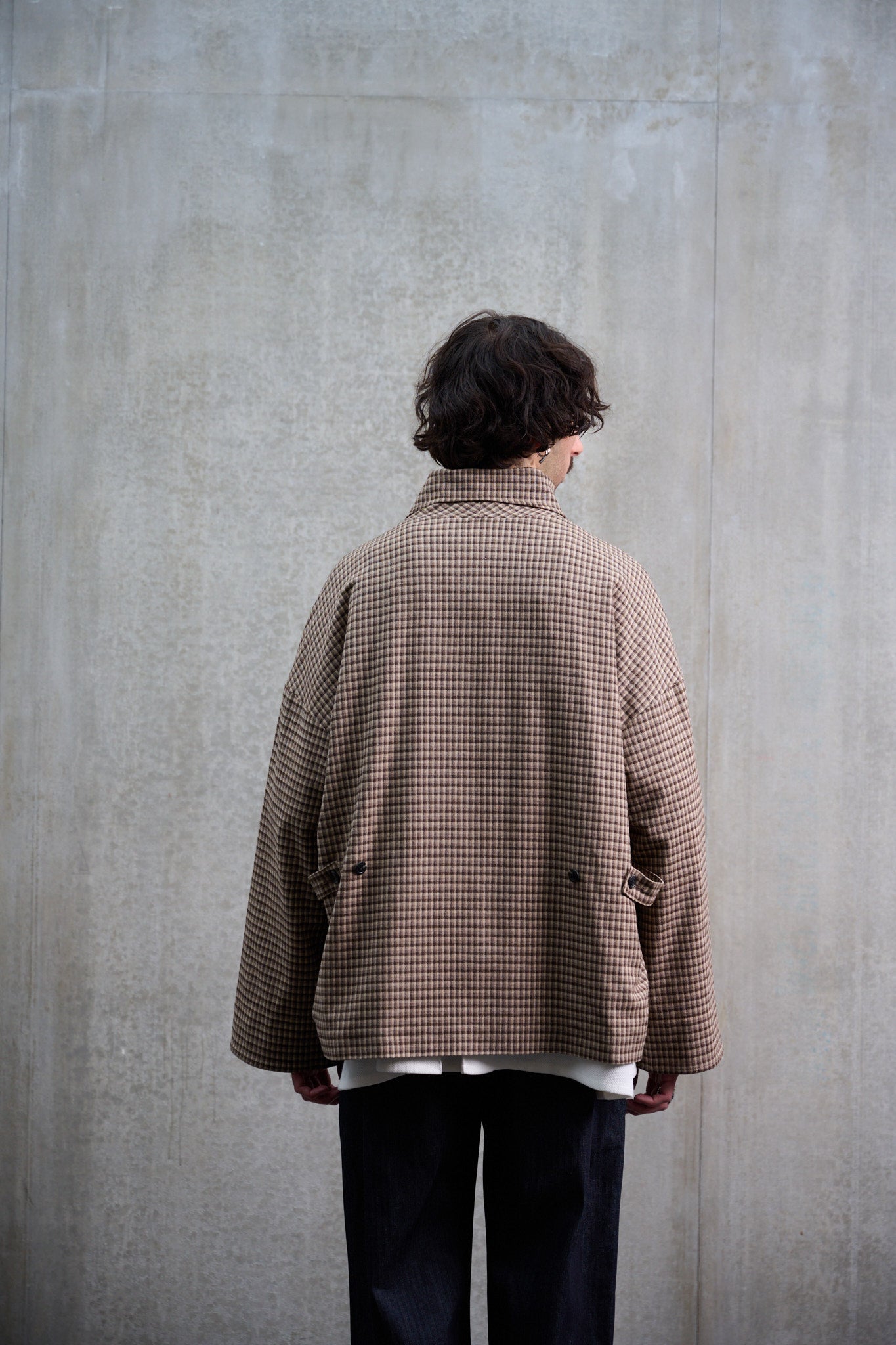 Veste oversize à col arrondi de la marque Aïdama, modèle Gunbai en laine marron à motif Vichy. Portée fermée par un mannequin homme et vue de dos.