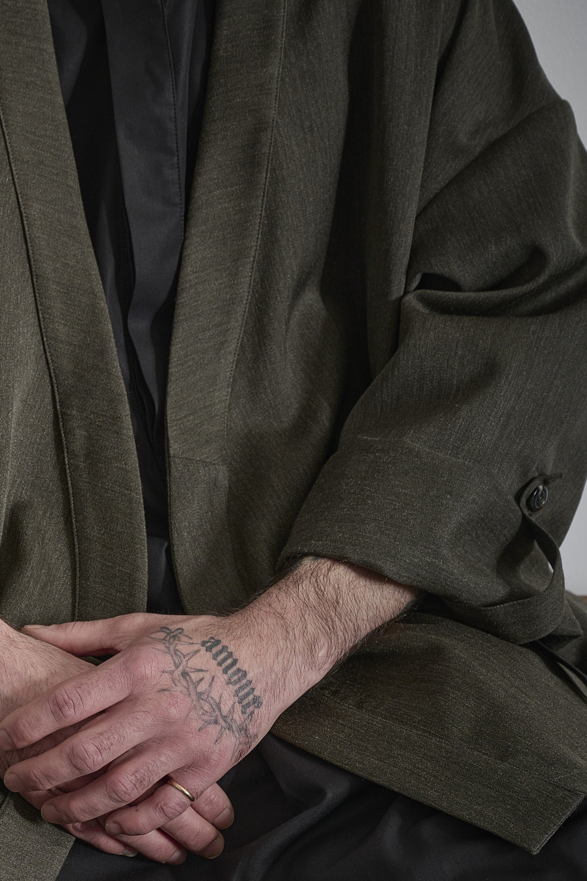 Veste croisée à col kimono de la marque Aïdama, modèle samue en laine froide vert chiné. Portée ouverte par un mannequin homme et vue zoomée sur la manche et le tissu.