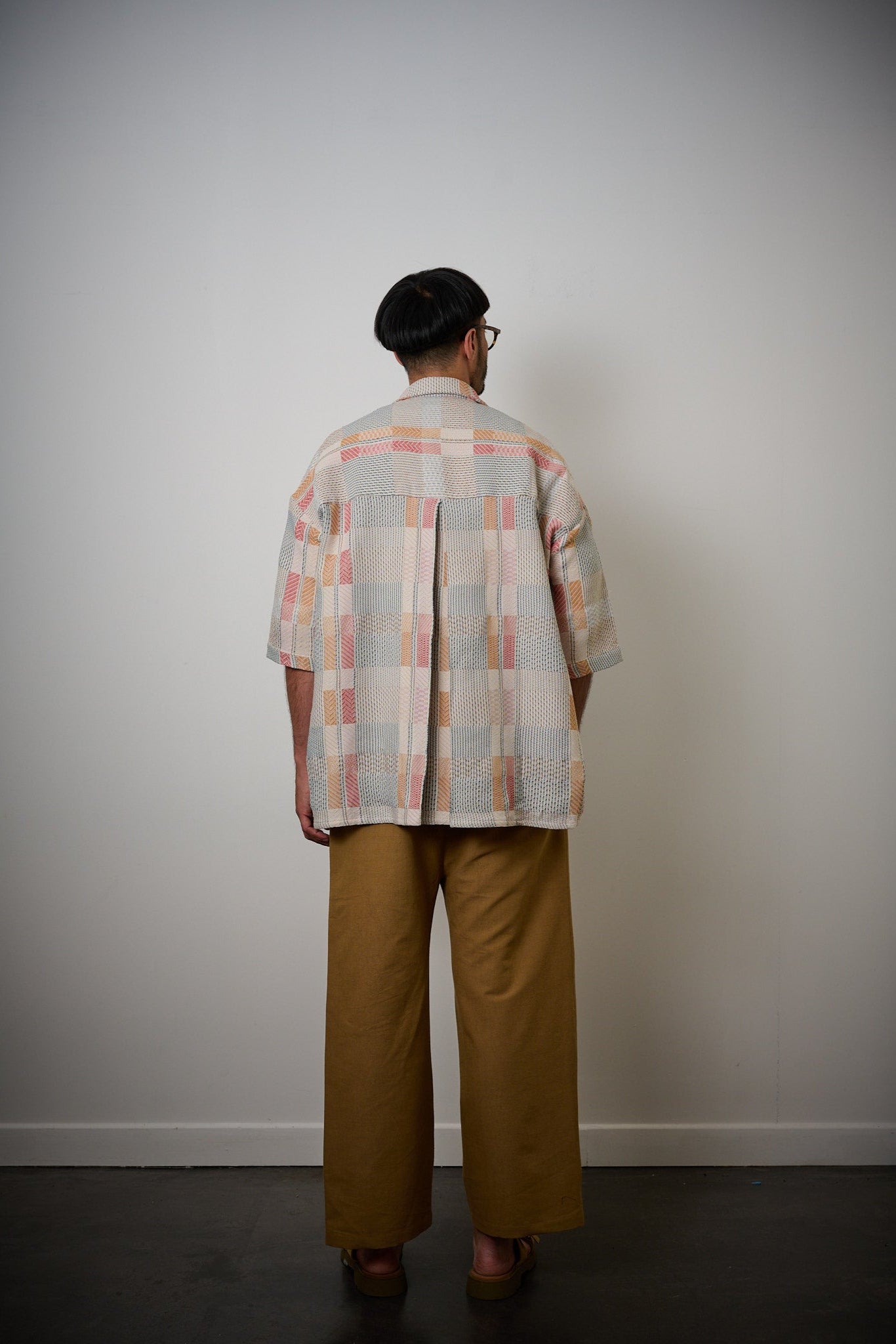 Chemise oversize à col club de la marque Aïdama en jacquard à carreaux fantaisies. Portée fermée par un mannequin homme et vue de dos.