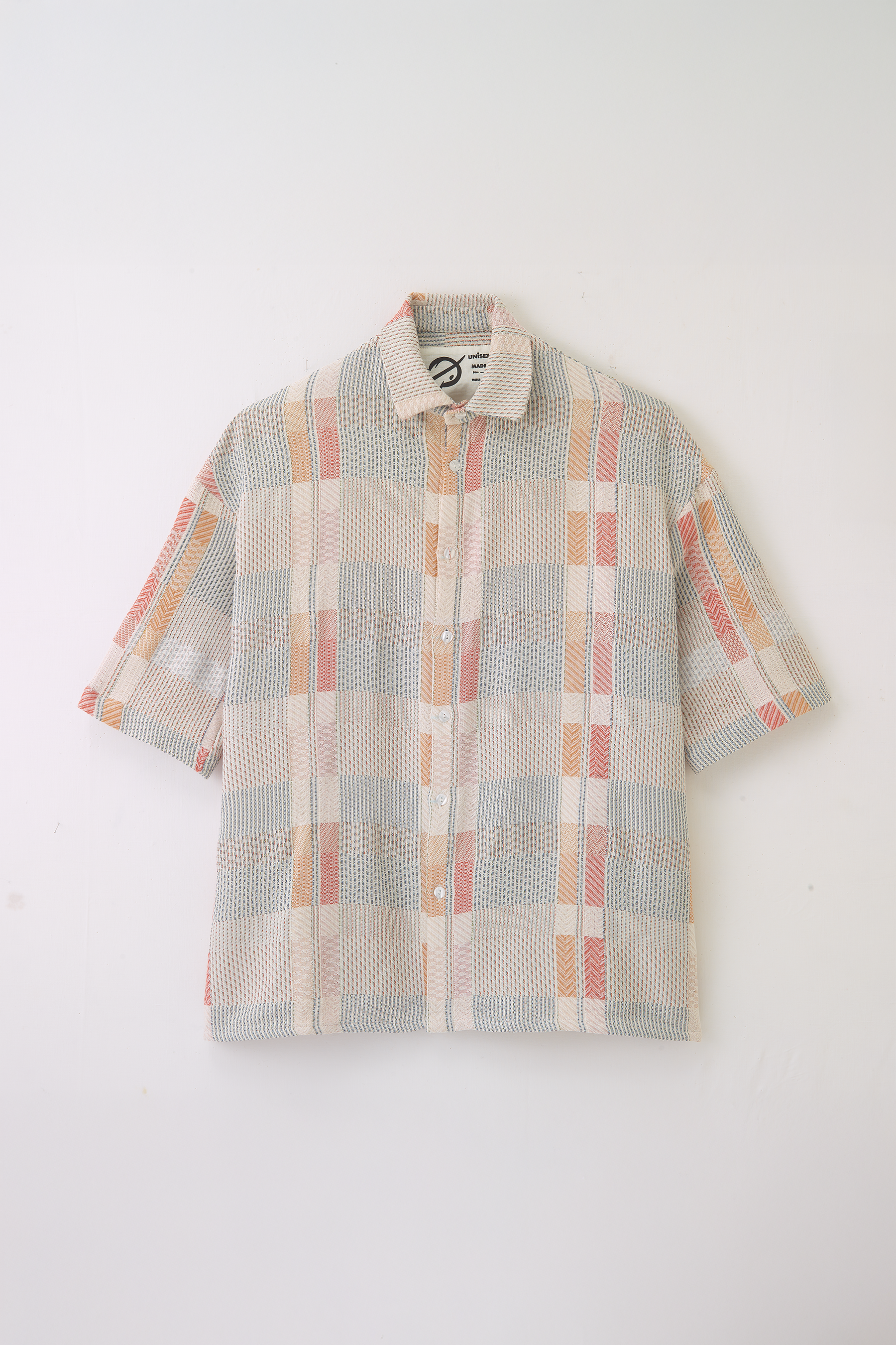 Chemise oversize à col club de la marque Aïdama en jacquard à carreaux fantaisies. Vue fermée à plat sur fond blanc.