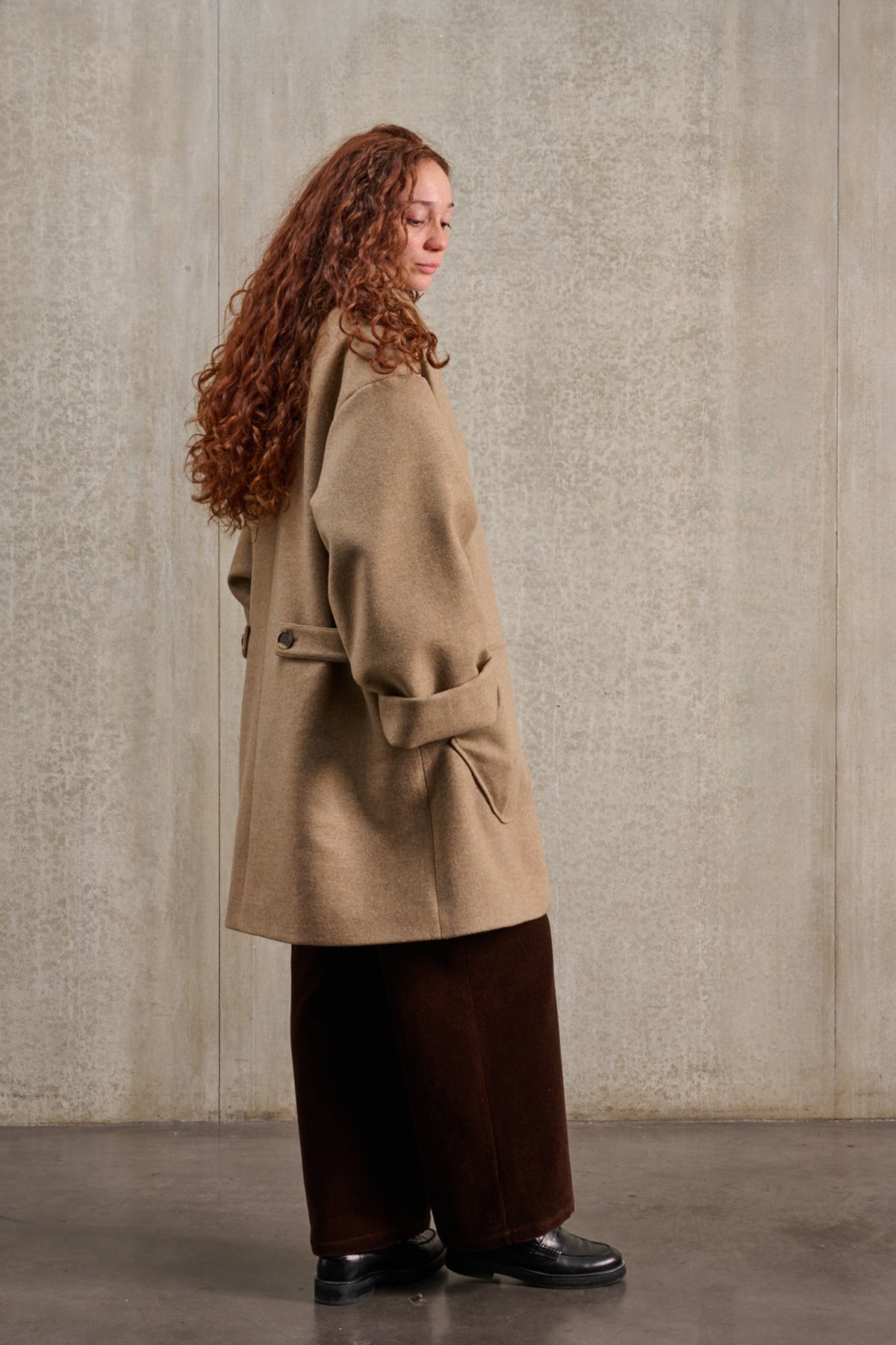 Manteau croisé oversize de la marque Aïdama, modèle Haomi en laine et cachemire beige. Porté fermé par une mannequin femme et vu de profil.