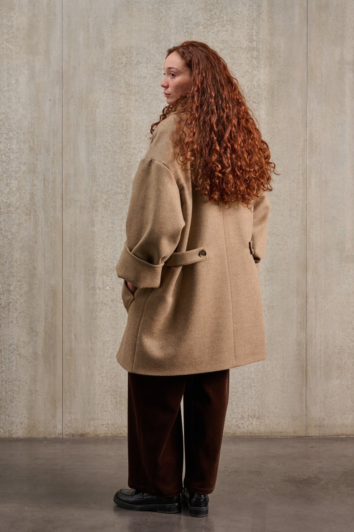 Manteau croisé oversize de la marque Aïdama, modèle Haomi en laine et cachemire beige. Porté ouvert par une mannequin femme et vu de dos.