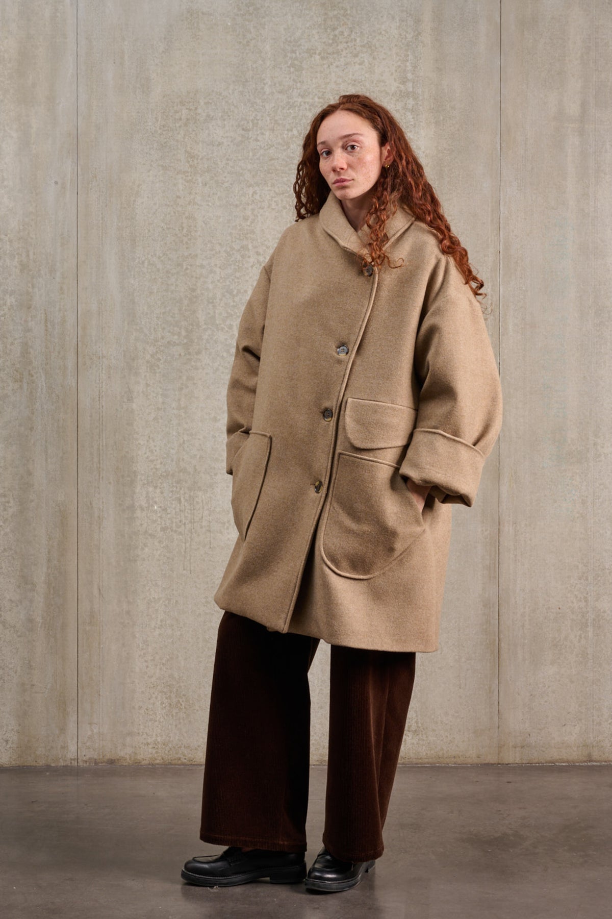 Manteau croisé oversize de la marque Aïdama, modèle Haomi en laine et cachemire beige. Porté fermé par une mannequin femme et vu de trois quarts.