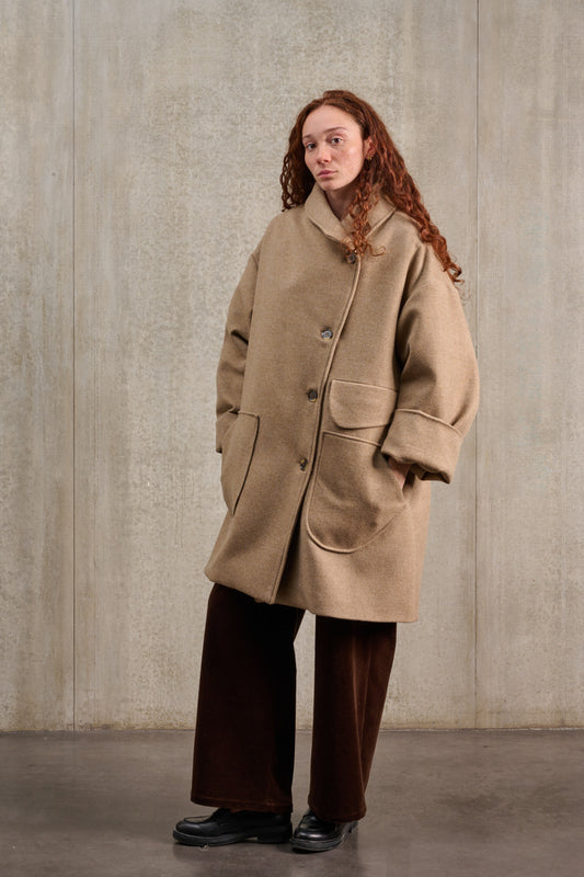 Manteau croisé oversize de la marque Aïdama, modèle Haomi en laine et cachemire beige. Porté fermé par une mannequin femme et vu de trois quarts.