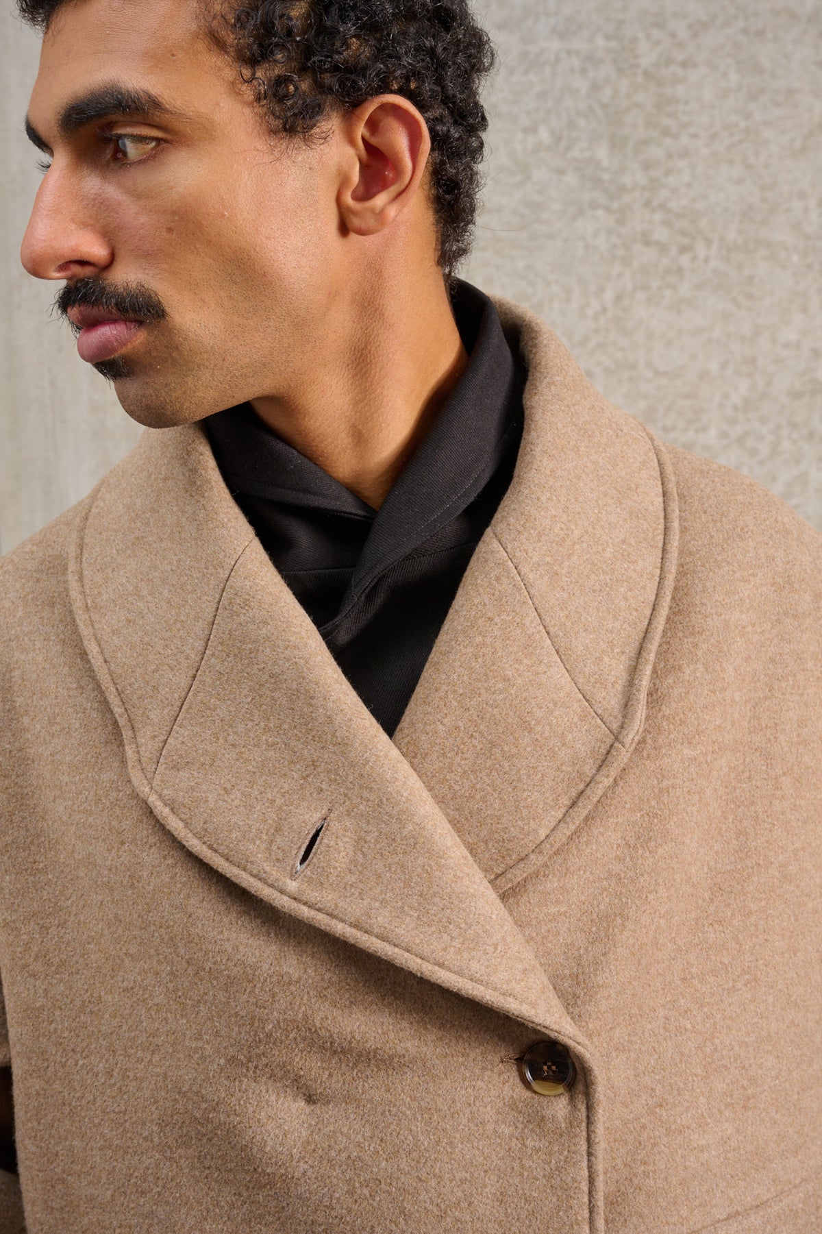 Manteau croisé oversize de la marque Aïdama, modèle Haomi en laine et cachemire beige. Porté fermé par un mannequin homme et vu de face, centré sur le col.