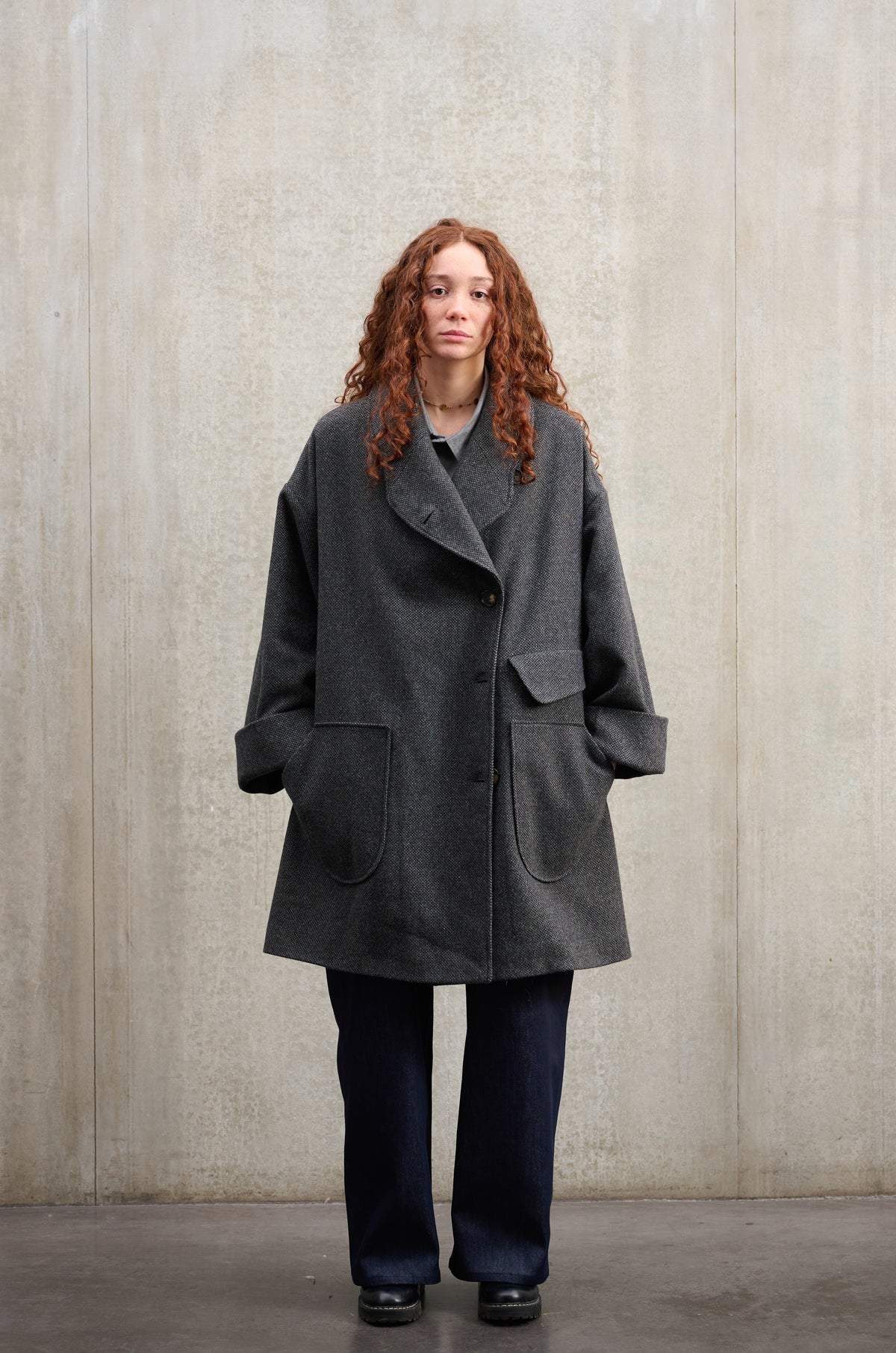 Manteau croisé oversize de la marque Aïdama, modèle Haomi en laine à micro motif damier gris et noir. Porté fermé par une mannequin femme et vu de face.