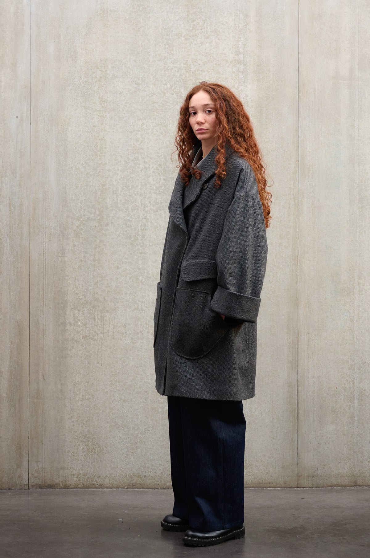 Manteau croisé oversize de la marque Aïdama, modèle Haomi en laine à micro motif damier gris et noir. Porté ouvert par une mannequin femme et vu de trois quarts.