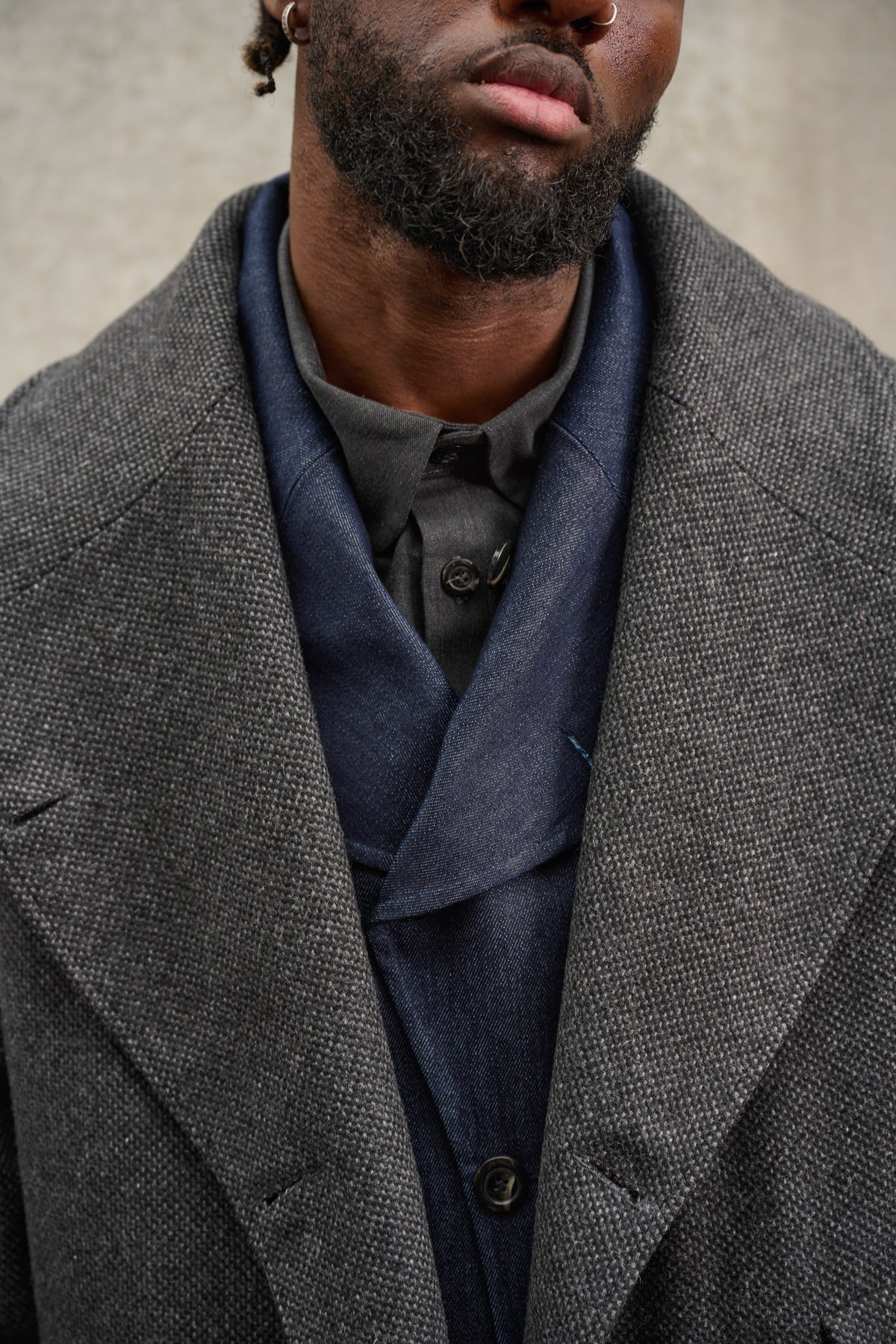 Manteau croisé oversize de la marque Aïdama, modèle Haomi en laine à micro motif damier gris et noir. Porté ouvert par un mannequin homme et vu centré sur le col.