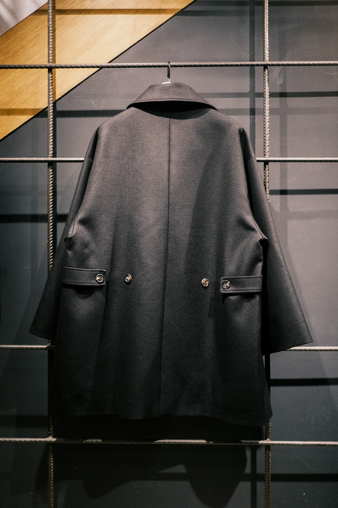 Manteau croisé oversize de la marque Aïdama, modèle Haomi en laine noire. Vu sur ceintre et de dos.