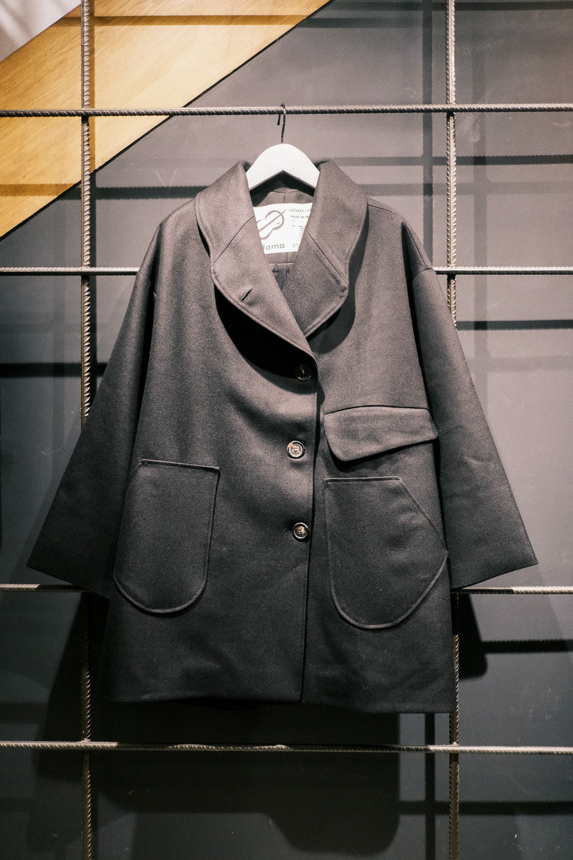 Manteau croisé oversize de la marque Aïdama, modèle Haomi en laine noire. Vu sur ceintre de face.