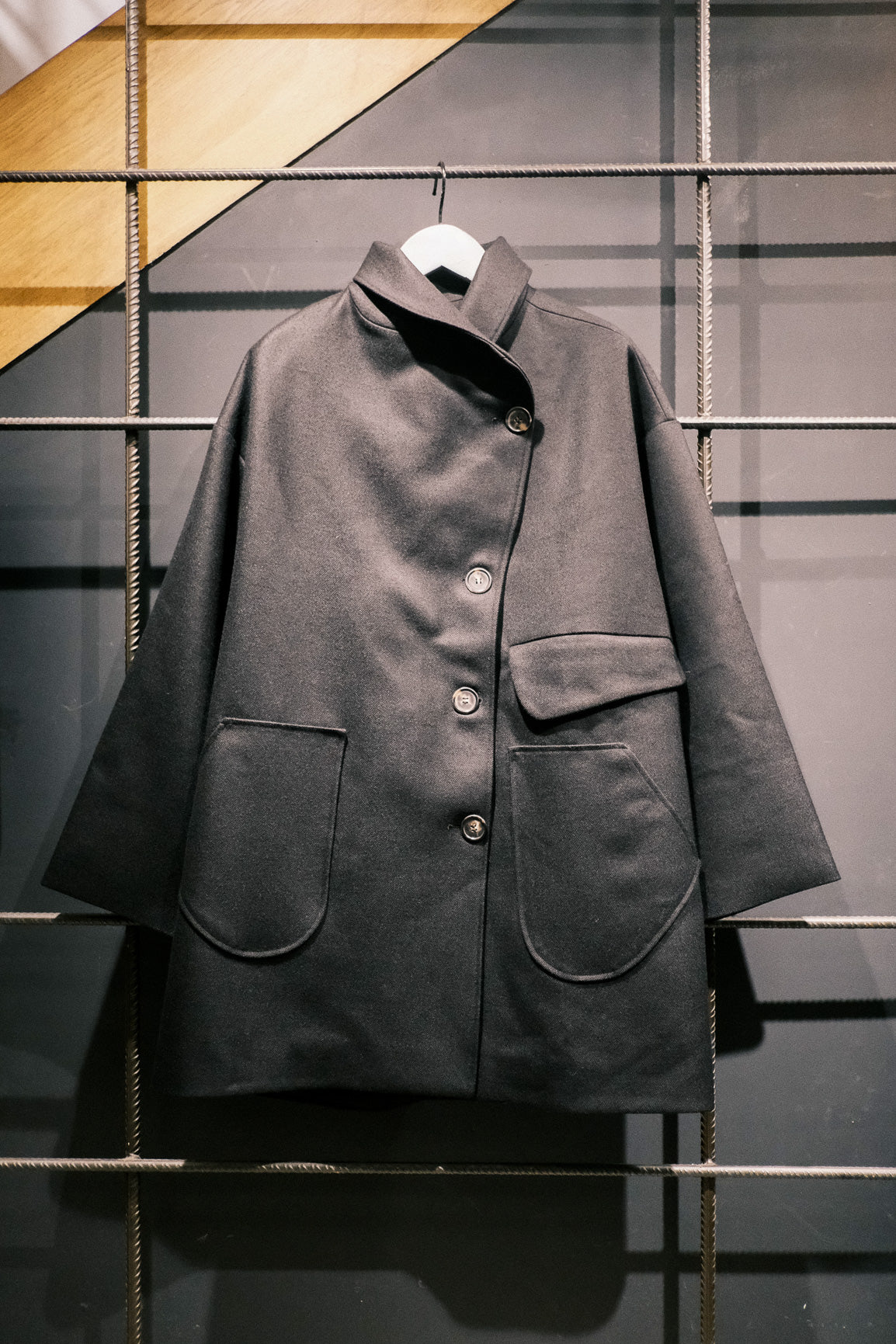 Manteau croisé oversize de la marque Aïdama, modèle Haomi en laine noire. Vu sur ceintre fermé et de face.