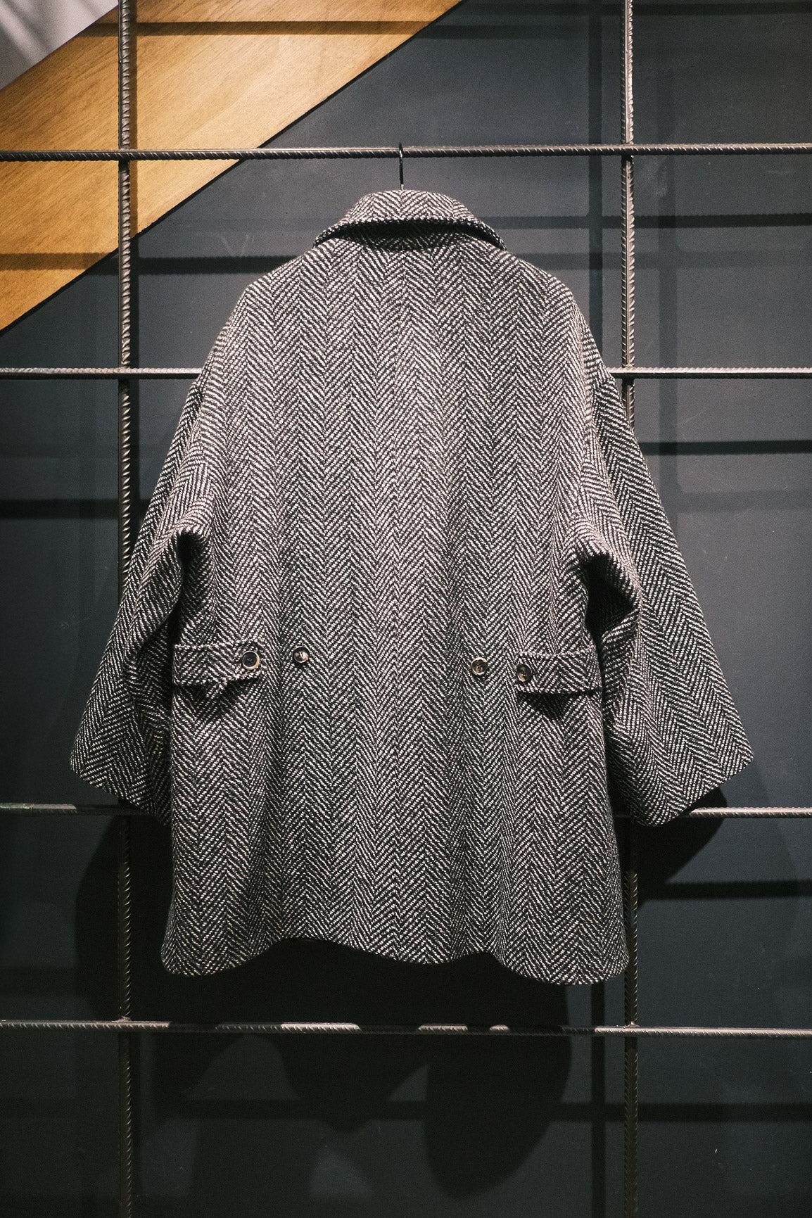 Manteau croisé oversize de la marque Aïdama, modèle Haomi en tweed de laine gris à motif chevrons. Vue sur ceintre de dos.