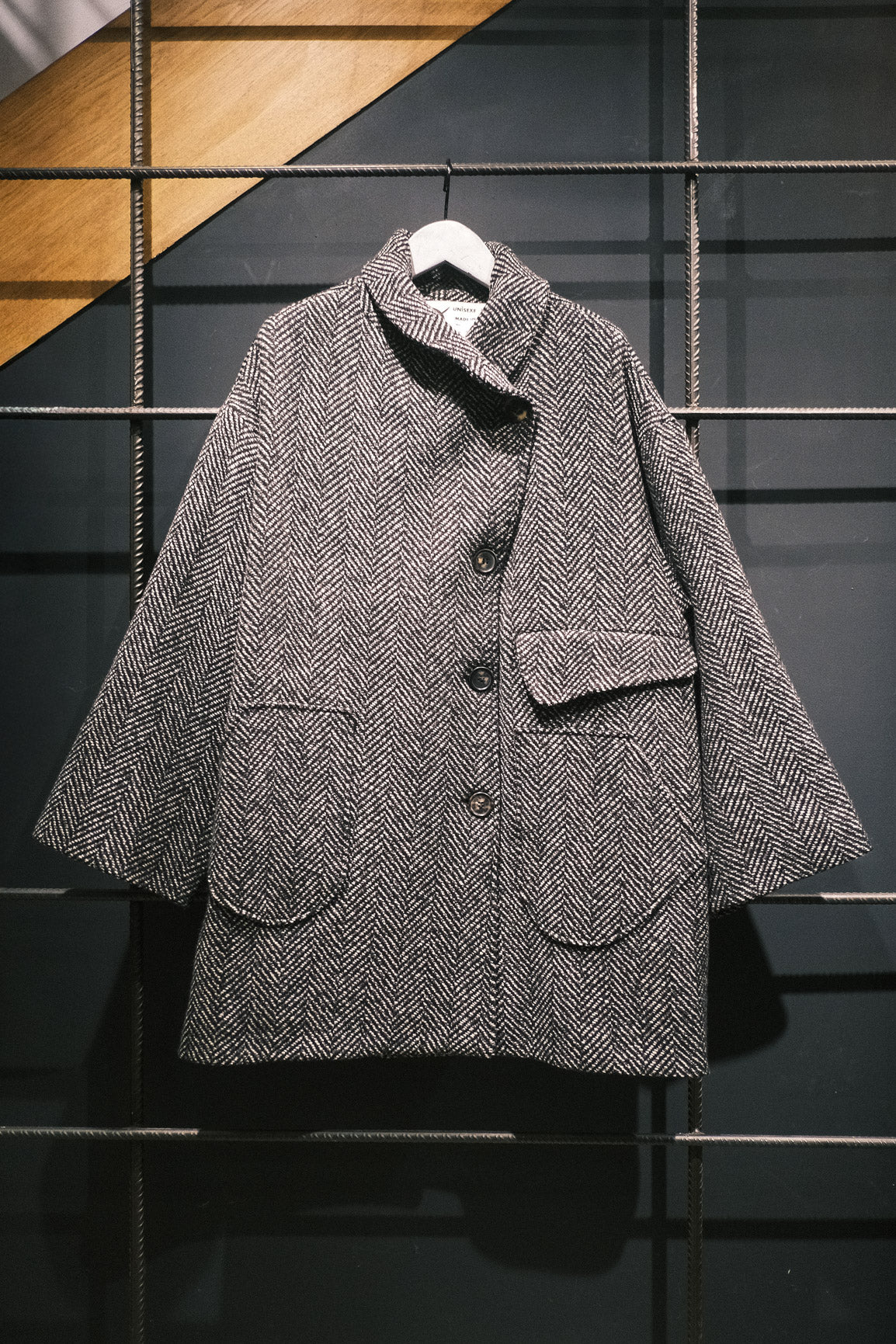 Manteau croisé oversize de la marque Aïdama, modèle Haomi en tweed de laine gris à motif chevrons. Vue sur ceintre de face.