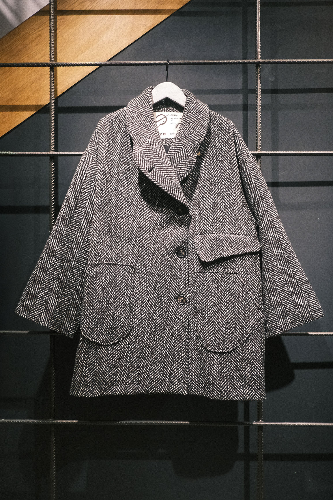 Manteau croisé oversize de la marque Aïdama, modèle Haomi en tweed de laine gris à motif chevrons. Vue sur ceintre de face.