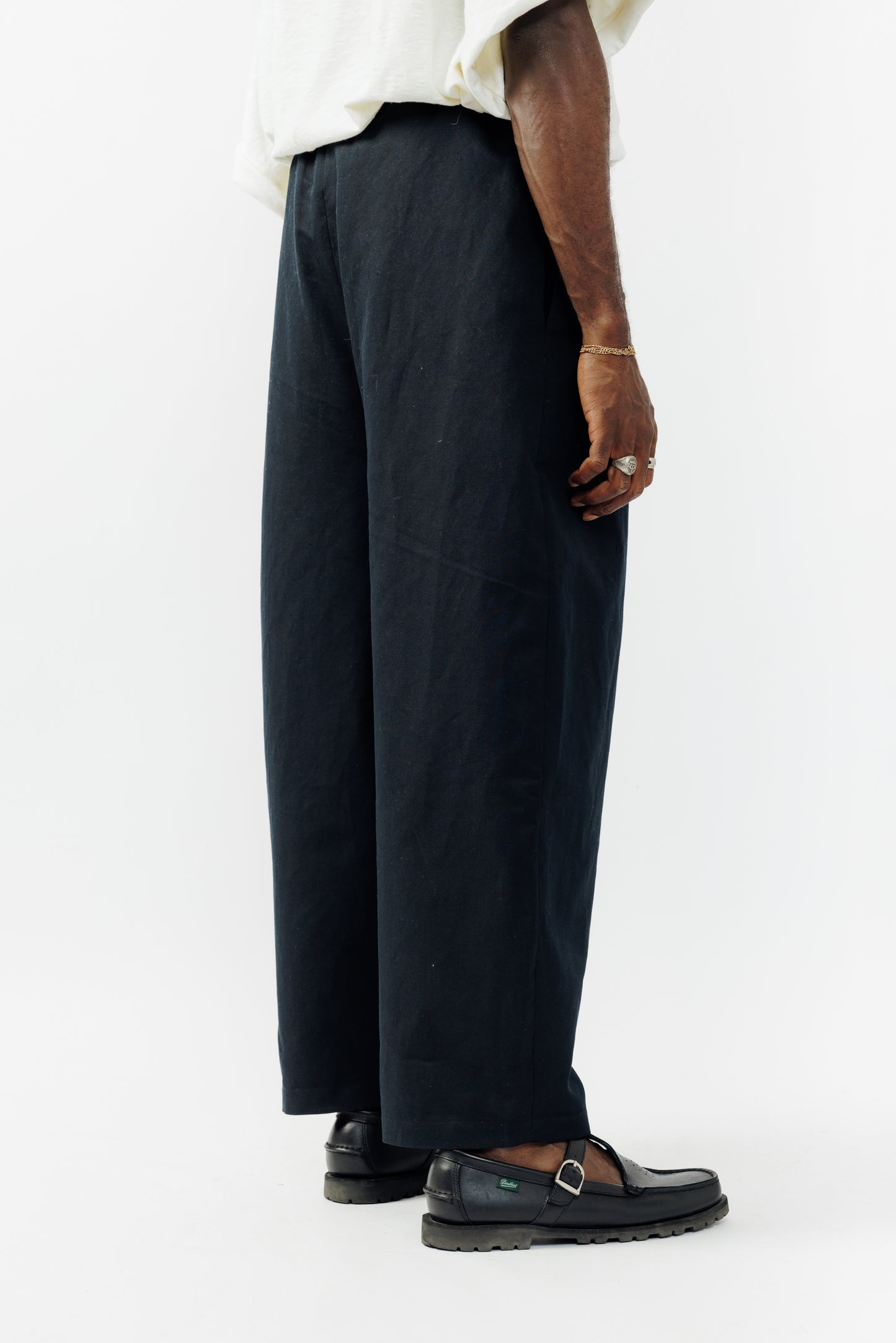 Pantalon circulaire de la marque Aïdama, coupe ballon en coton et lin noir avec ceinture ajustable. Porté par un mannequin homme et vu de dos