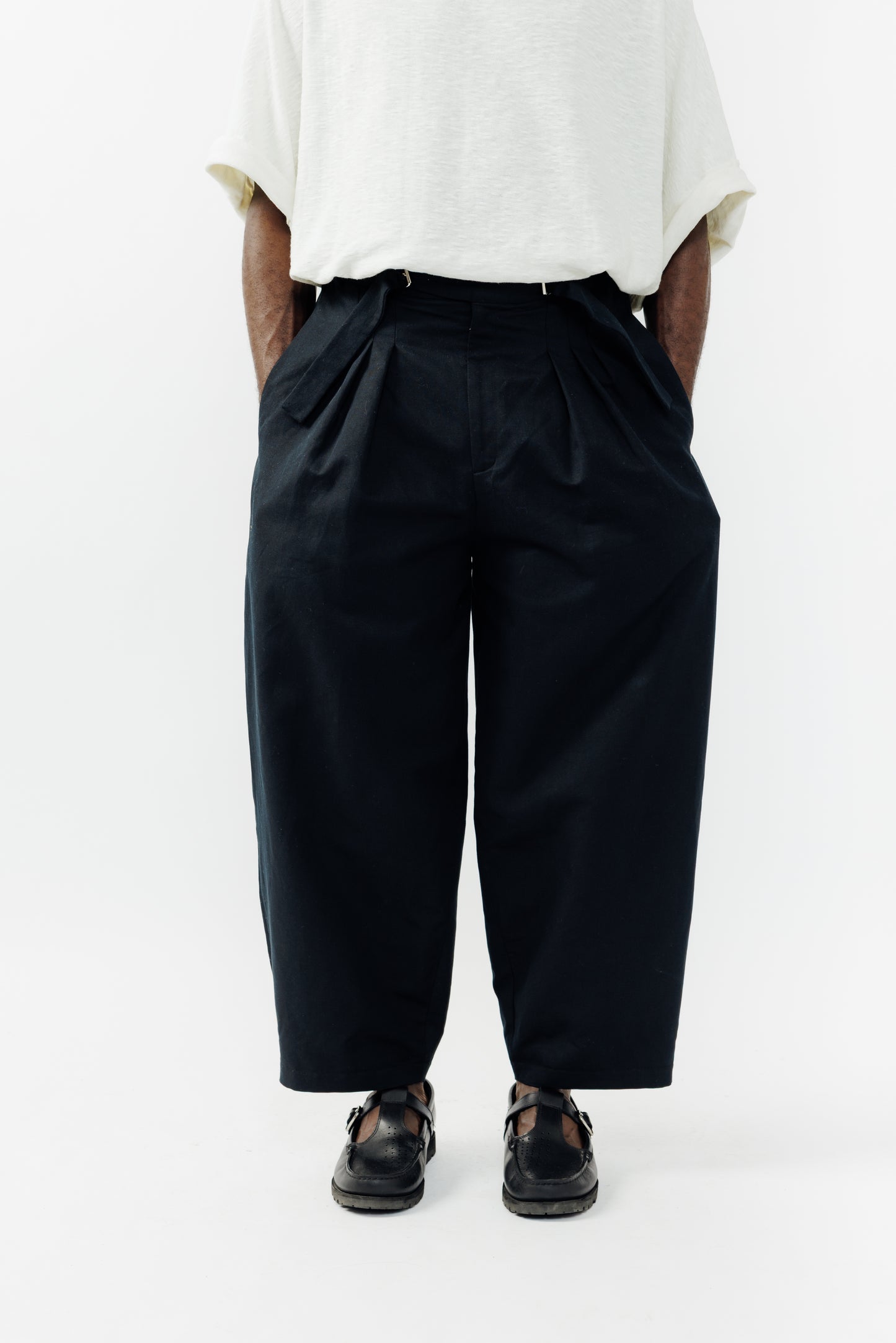Pantalon circulaire de la marque Aïdama, coupe ballon en coton et lin noir avec ceinture ajustable. Porté par un mannequin homme et vu zoomé sur les jambes.