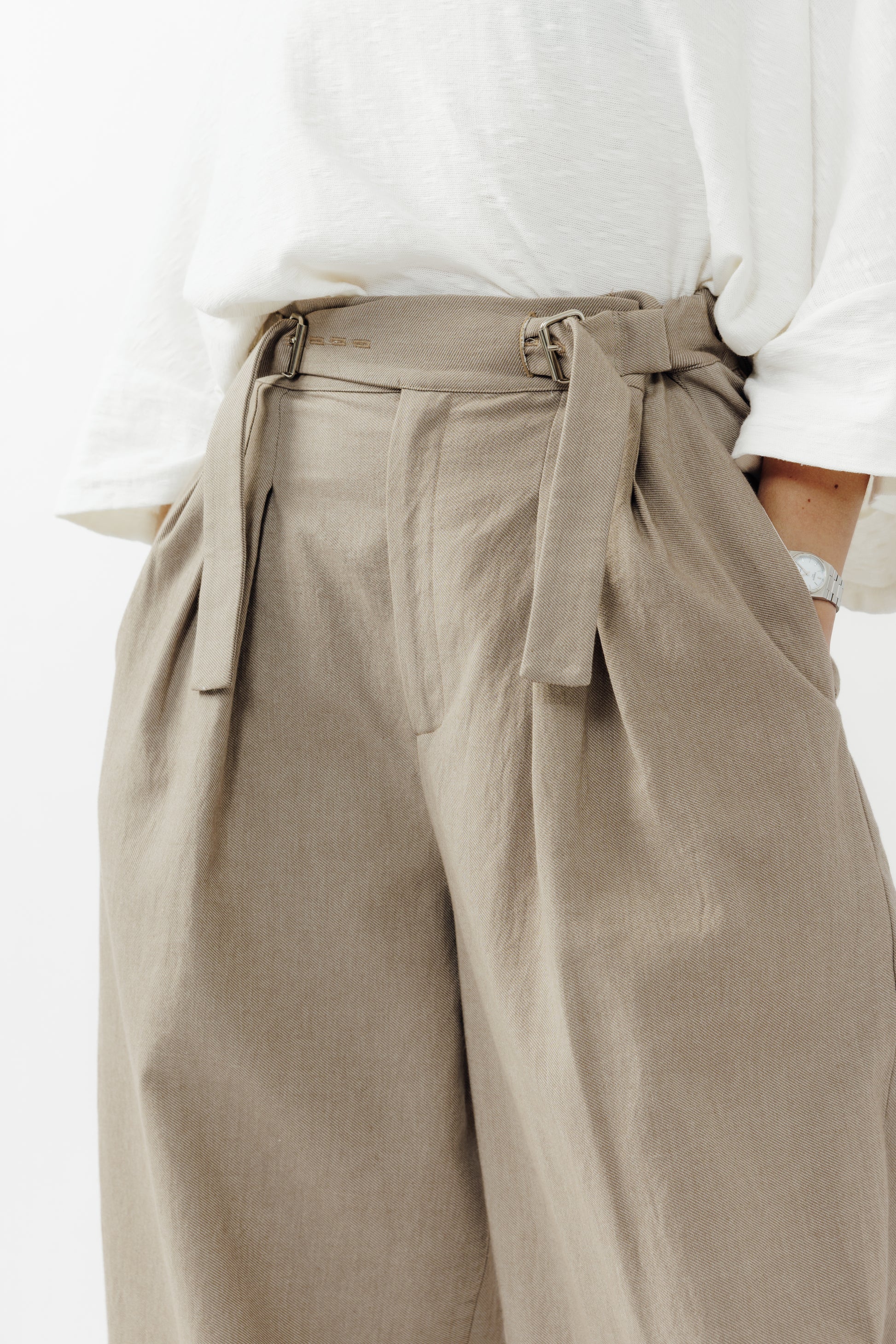 Pantalon circulaire de la marque Aïdama, coupe ballon en coton marron glacé avec ceinture ajustable. Porté par une mannequin femme et vu de face zoomé sur la ceinture.
