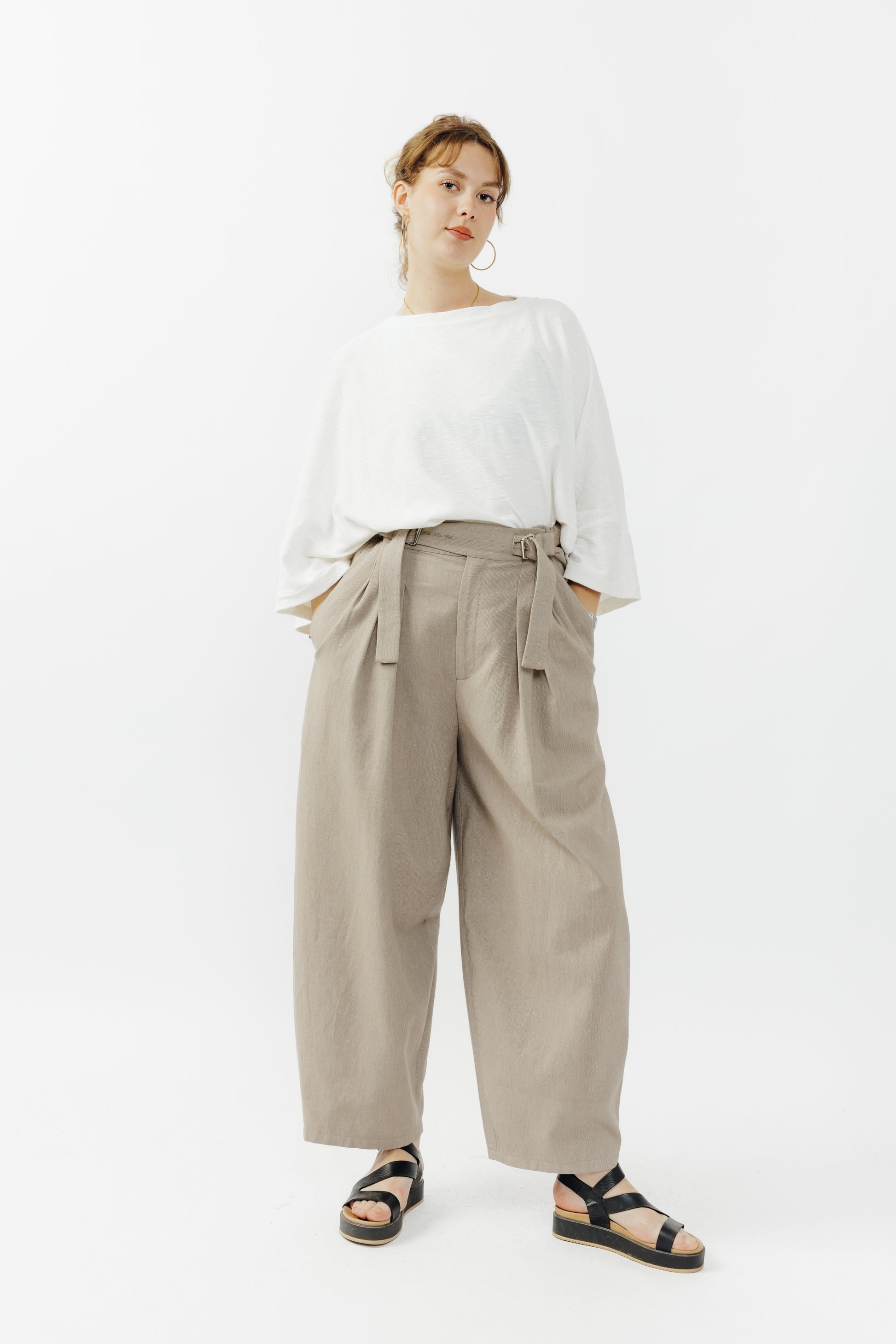 Pantalon circulaire de la marque Aïdama, coupe ballon en coton marron glacé avec ceinture ajustable. Porté par une mannequin femme et vu de face. 