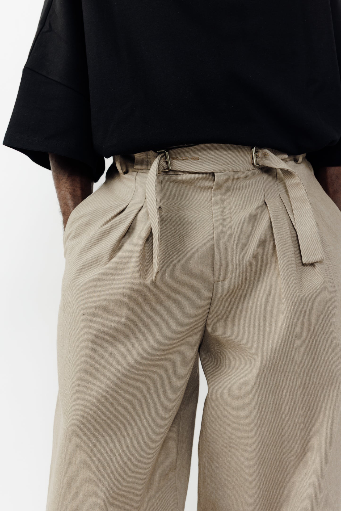 Pantalon circulaire de la marque Aïdama, coupe ballon en coton marron glacé avec ceinture ajustable. Porté par un mannequin homme et vu de face zoomé sur la ceinture.