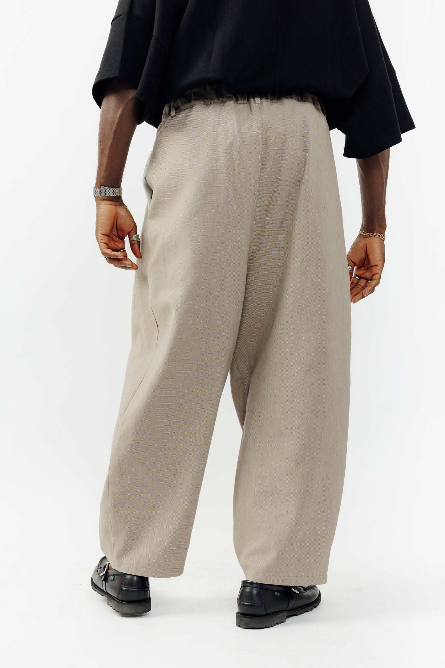 Pantalon circulaire de la marque Aïdama, coupe ballon en coton marron glacé avec ceinture ajustable. Porté par un mannequin homme et vu de dos.
