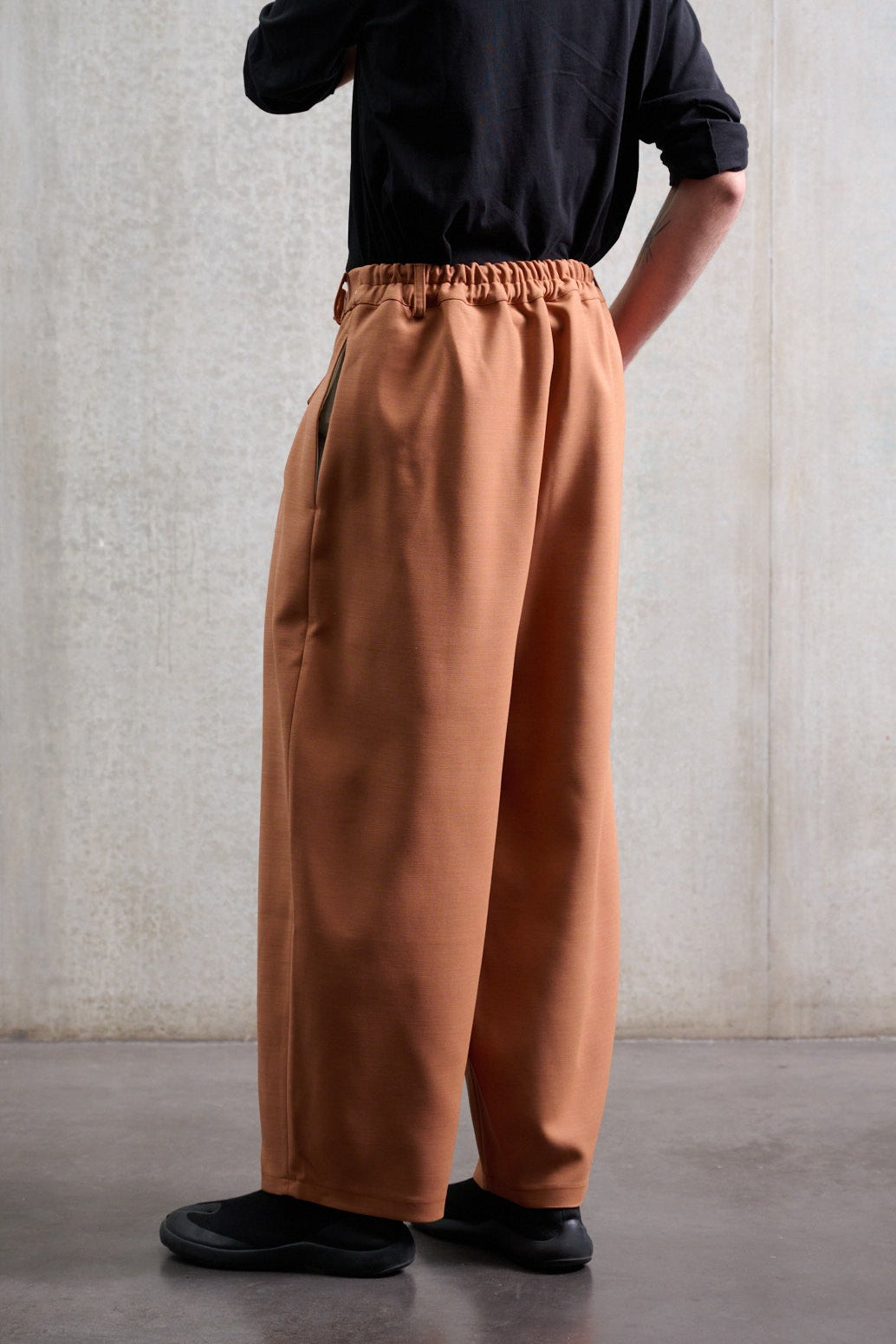 Pantalon circulaire Aïdama, coupe ballon avec ceinture ajustable en coton & laine terre de sienne. Porté par un mannequin homme et vu de dos.