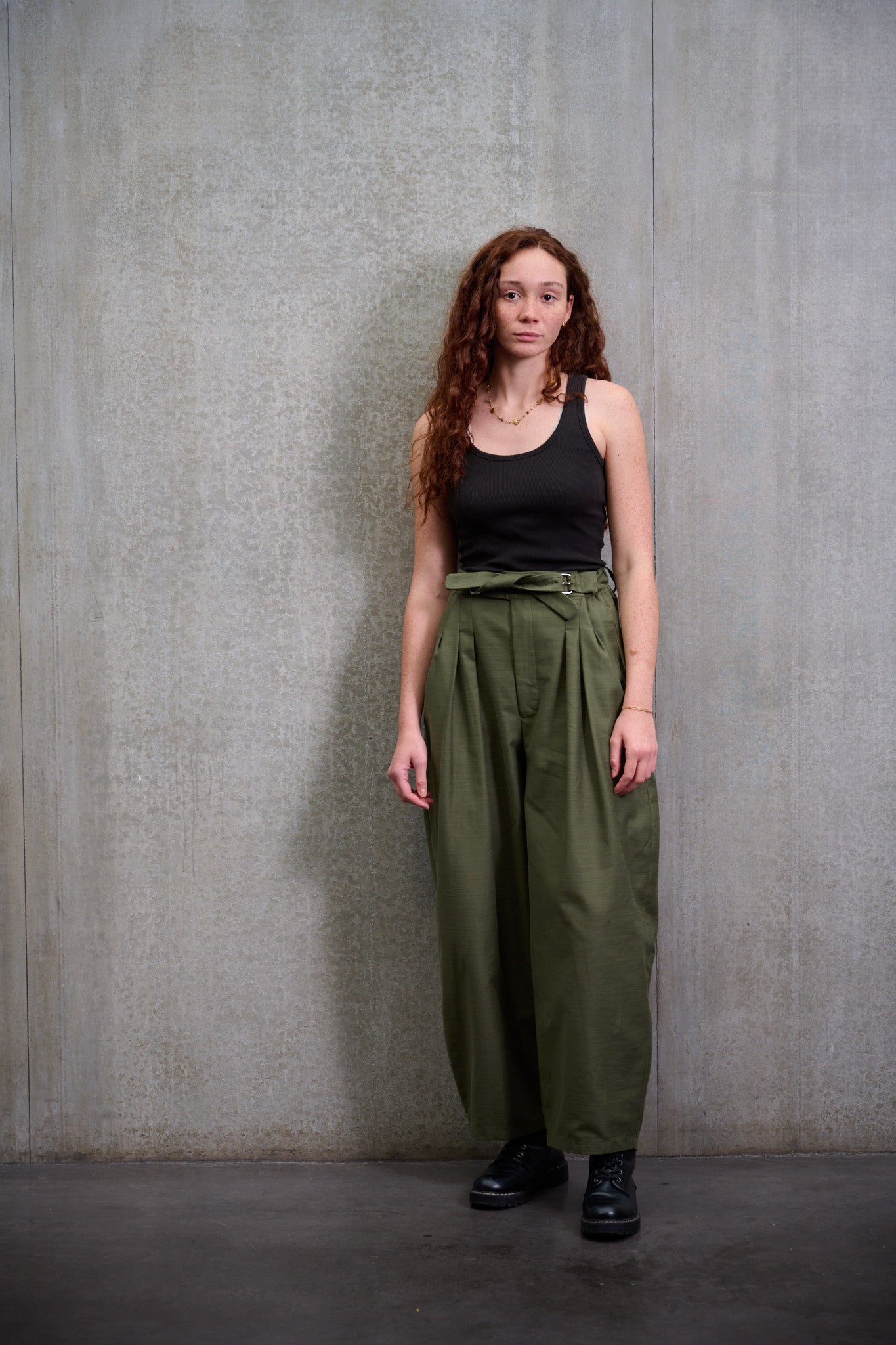 Pantalon circulaire Aïdama, coupe ballon avec ceinture ajustable en coton texturé vert. Porté par une mannequin femme et vu de face.