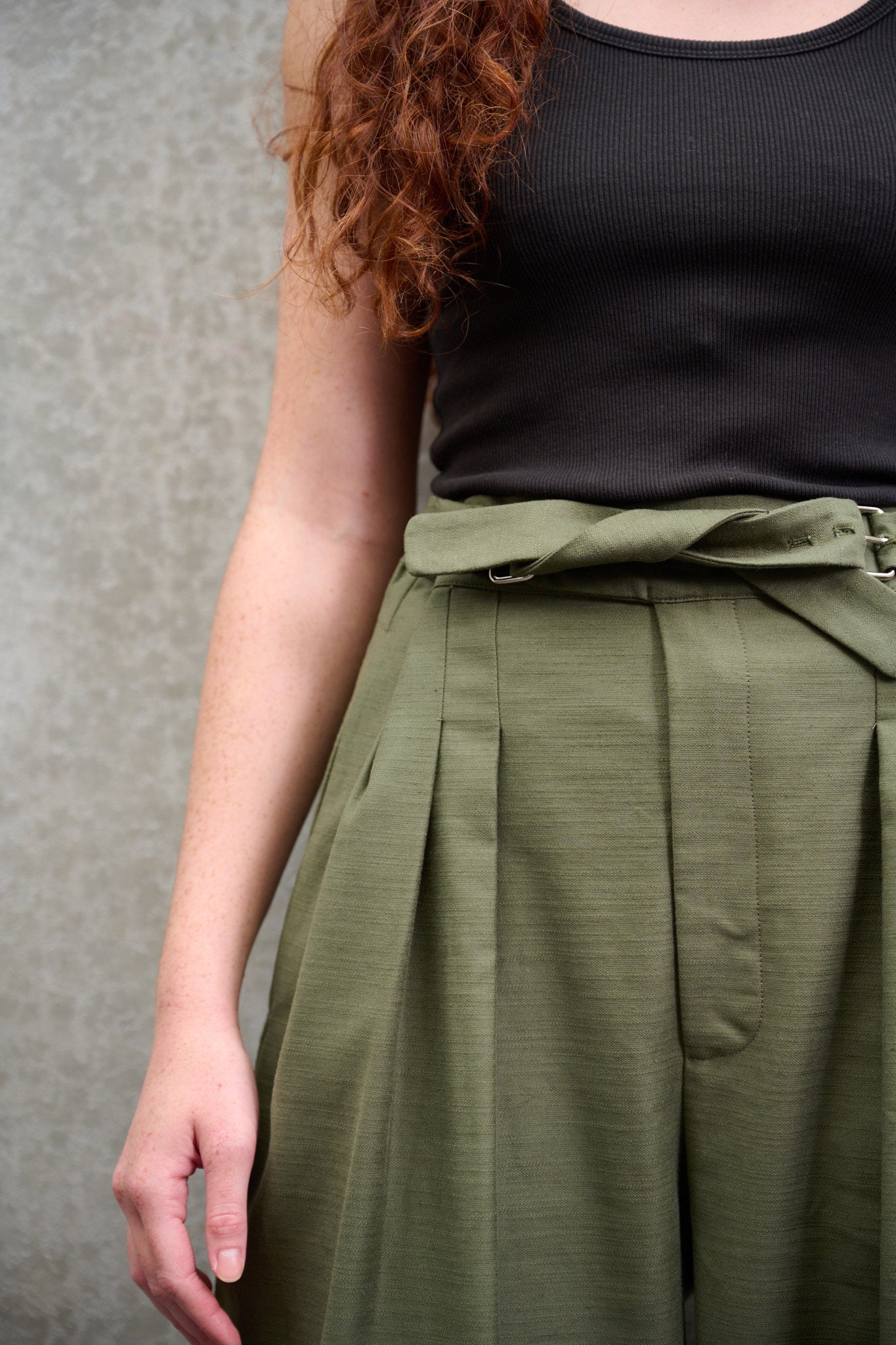 Pantalon circulaire Aïdama, coupe ballon avec ceinture ajustable en coton texturé vert. Porté par une mannequin femme et vu zoomé sur la ceinture.