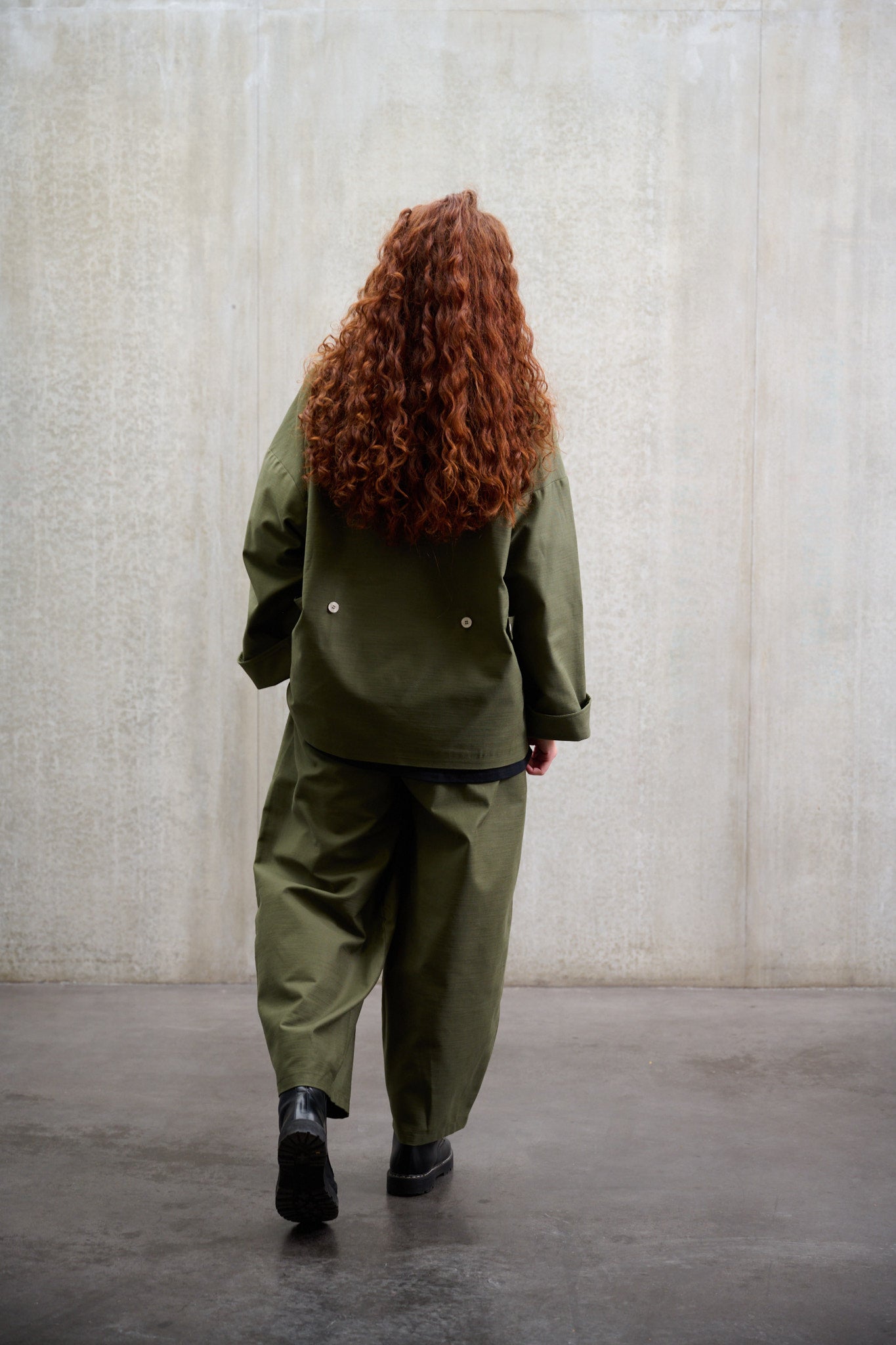 Pantalon circulaire Aïdama, coupe ballon avec ceinture ajustable en coton texturé vert. Porté par une mannequin femme et vu de dos. 