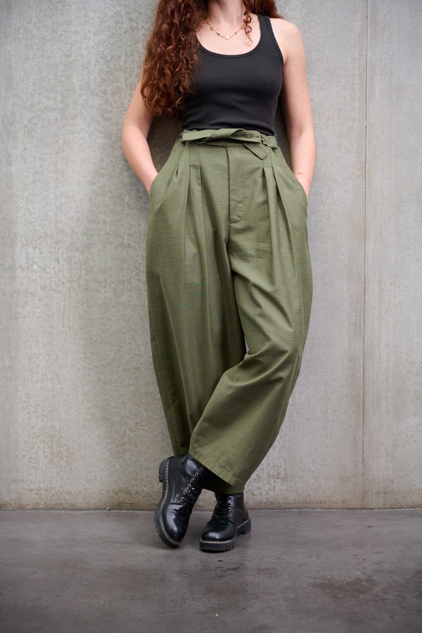 Pantalon circulaire Aïdama, coupe ballon avec ceinture ajustable en coton texturé vert. Porté par une mannequin femme et vu de face.