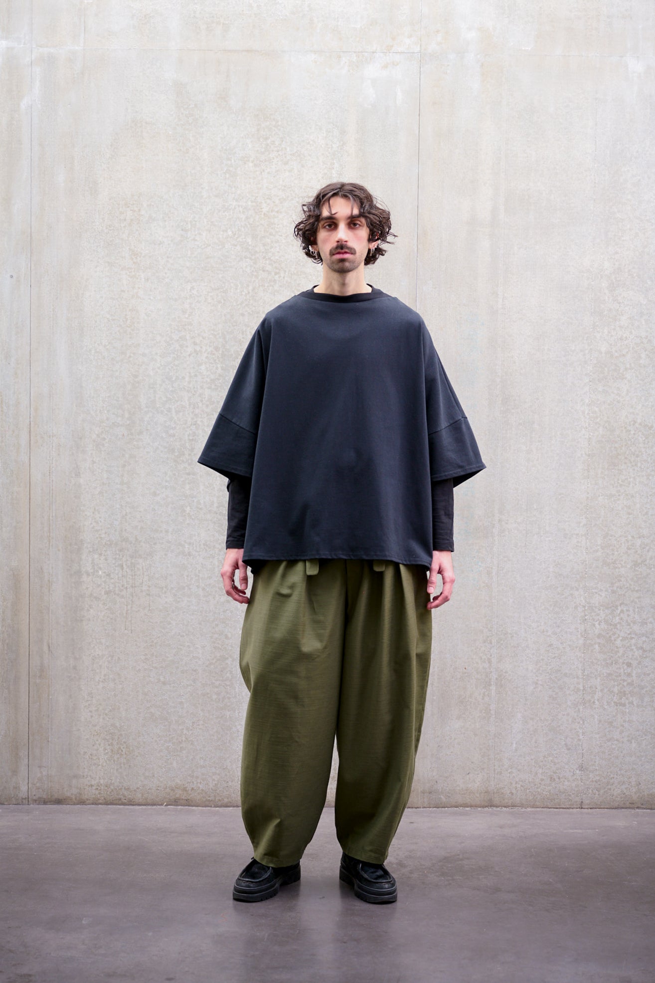 Pantalon circulaire Aïdama, coupe ballon avec ceinture ajustable en coton texturé vert. Porté par un mannequin homme et vu de face.
