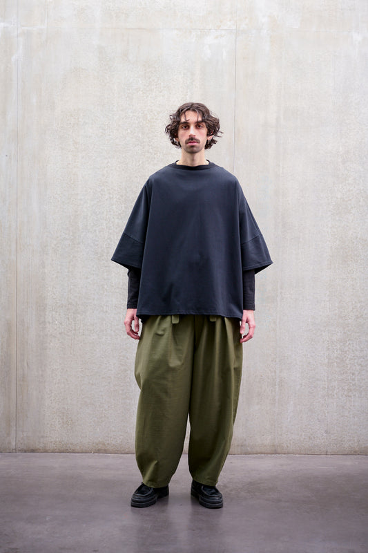 Pantalon circulaire Aïdama, coupe ballon avec ceinture ajustable en coton texturé vert. Porté par un mannequin homme et vu de face.