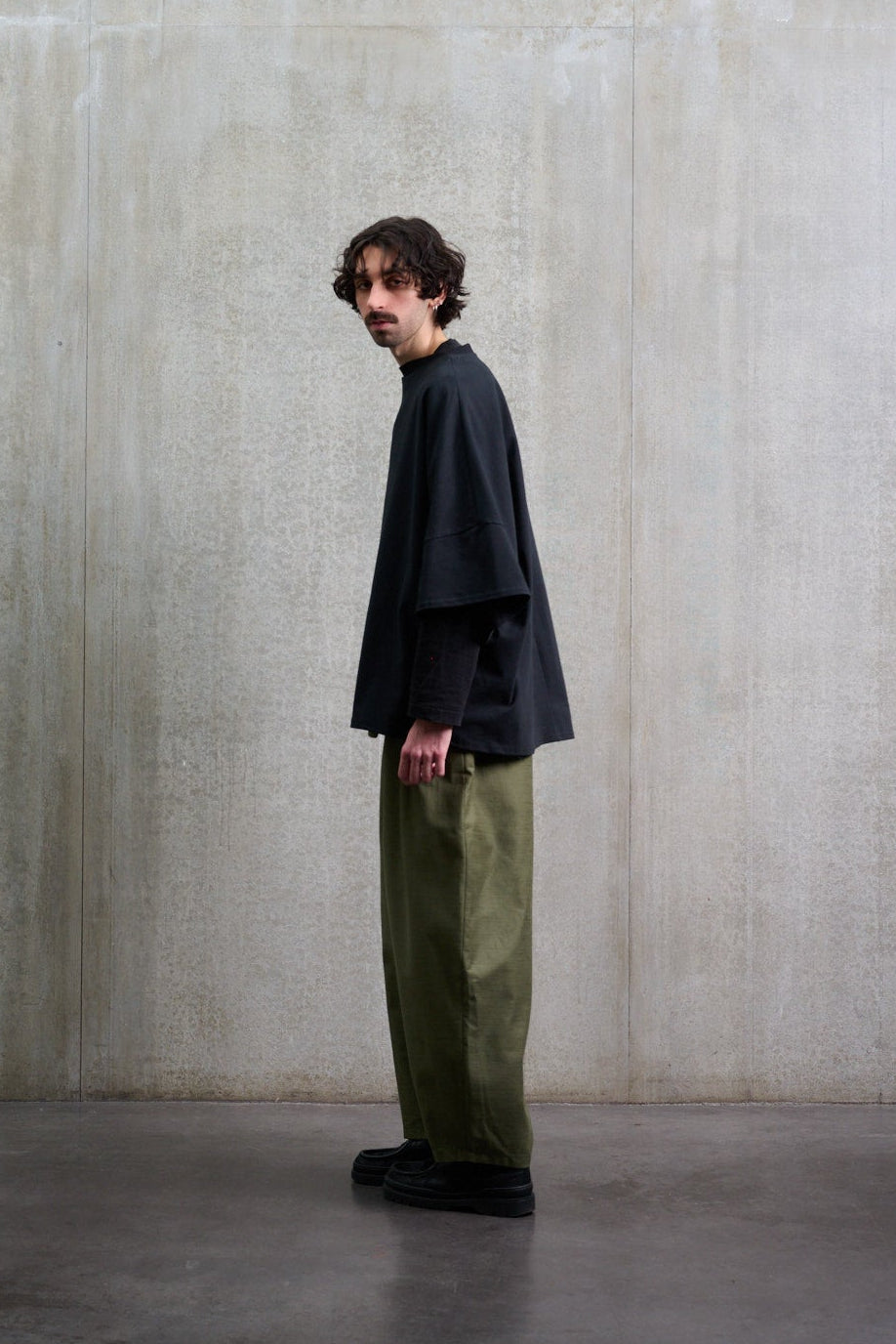 Pantalon circulaire Aïdama, coupe ballon avec ceinture ajustable en coton texturé vert. Porté par un mannequin homme et vu de profil. 