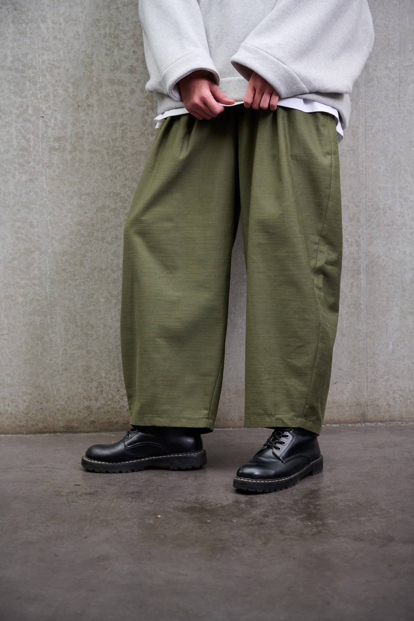 Pantalon circulaire Aïdama, coupe ballon avec ceinture ajustable en coton texturé vert. Porté par un mannequin homme et vu zoomé sur les jambes.