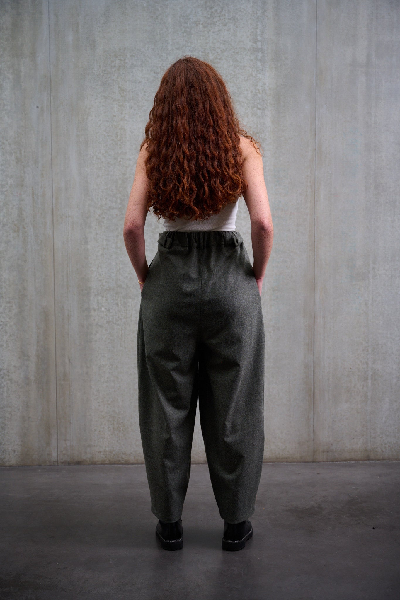 Pantalon circulaire Aïdama, coupe ballon avec ceinture ajustable en flanelle de laine gris chiné. Porté par une mannequin femme et vu de dos.