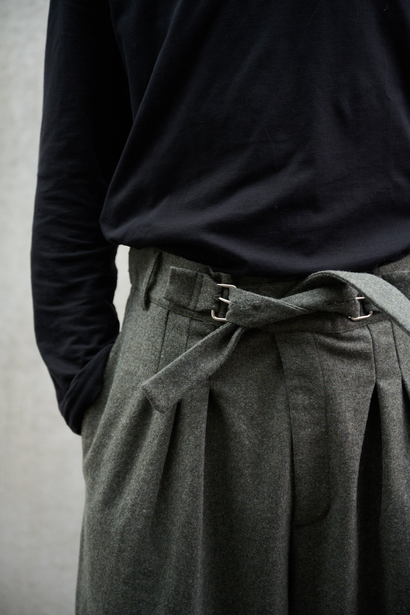 Pantalon circulaire Aïdama, coupe ballon avec ceinture ajustable en flanelle de laine gris chiné. Porté par un mannequin homme et vu de face zoomé sur la ceinture.
