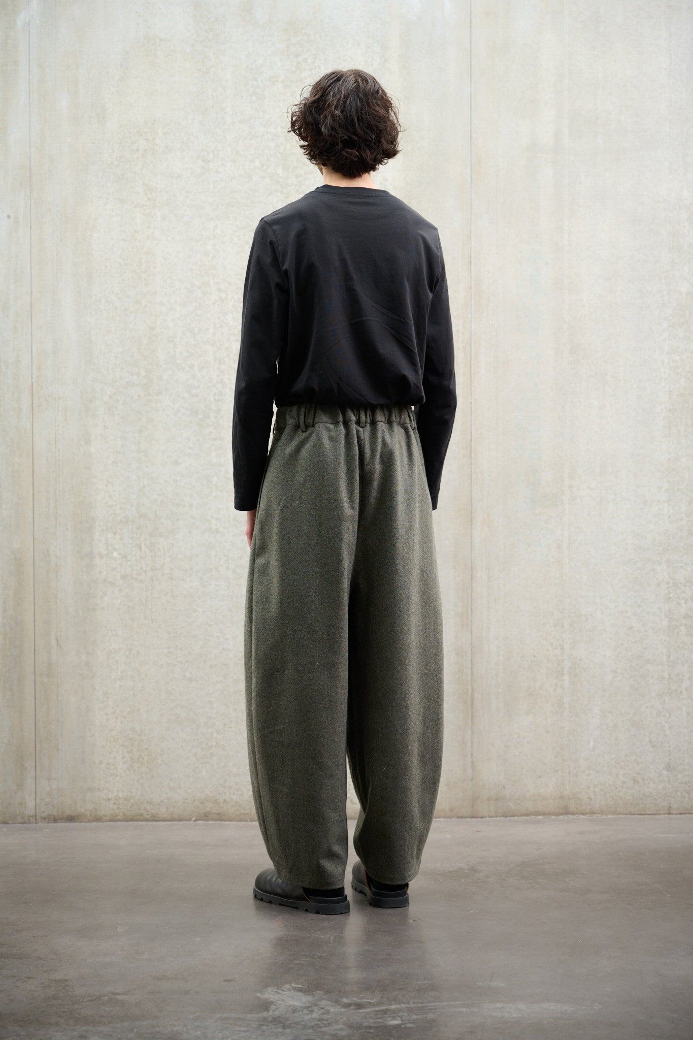 Pantalon circulaire Aïdama, coupe ballon avec ceinture ajustable en flanelle de laine gris chiné. Porté par un mannequin homme et vu de dos.
