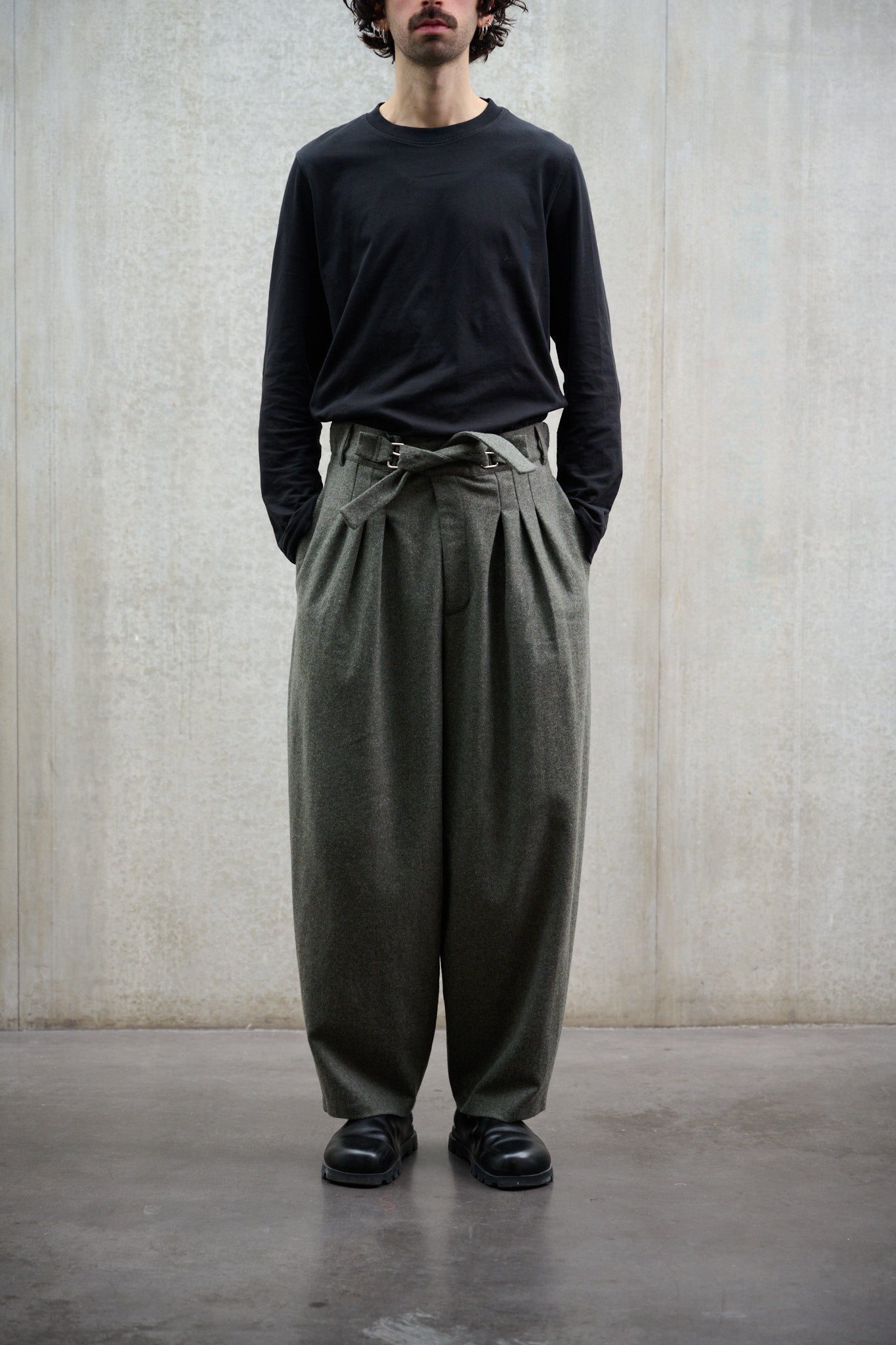 Pantalon circulaire Aïdama, coupe ballon avec ceinture ajustable en flanelle de laine gris chiné. Porté par un mannequin homme et vu de face. 