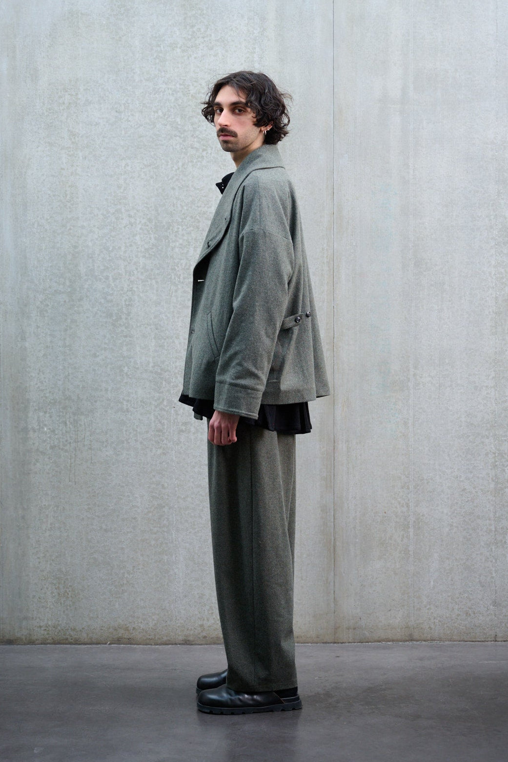 Pantalon circulaire Aïdama, coupe ballon avec ceinture ajustable en flanelle de laine gris chiné. Porté par un mannequin homme et vu de profil.