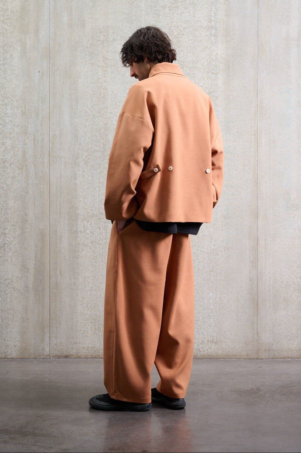 Ensemble pantalon circulaire coupe ballon Aïdama et veste oversize Gunbai en coton & laine terre de sienne. Porté par un mannequin homme et vu de dos.