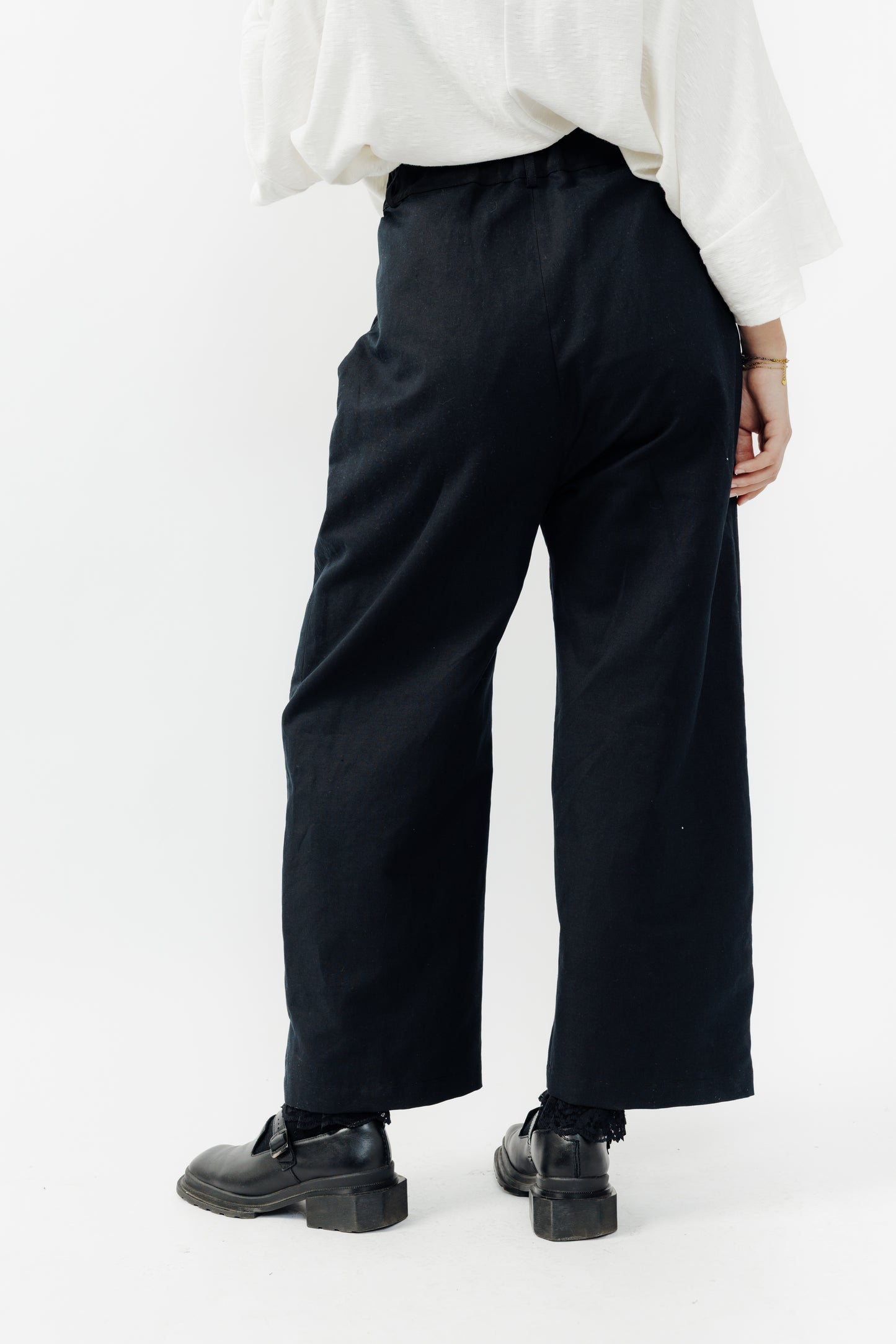 Pantalon droit de la marque Aïdama, coupe ample en coton et lin noir avec sangles ajustables à la taille. Porté par une mannequin femme et vu de face.