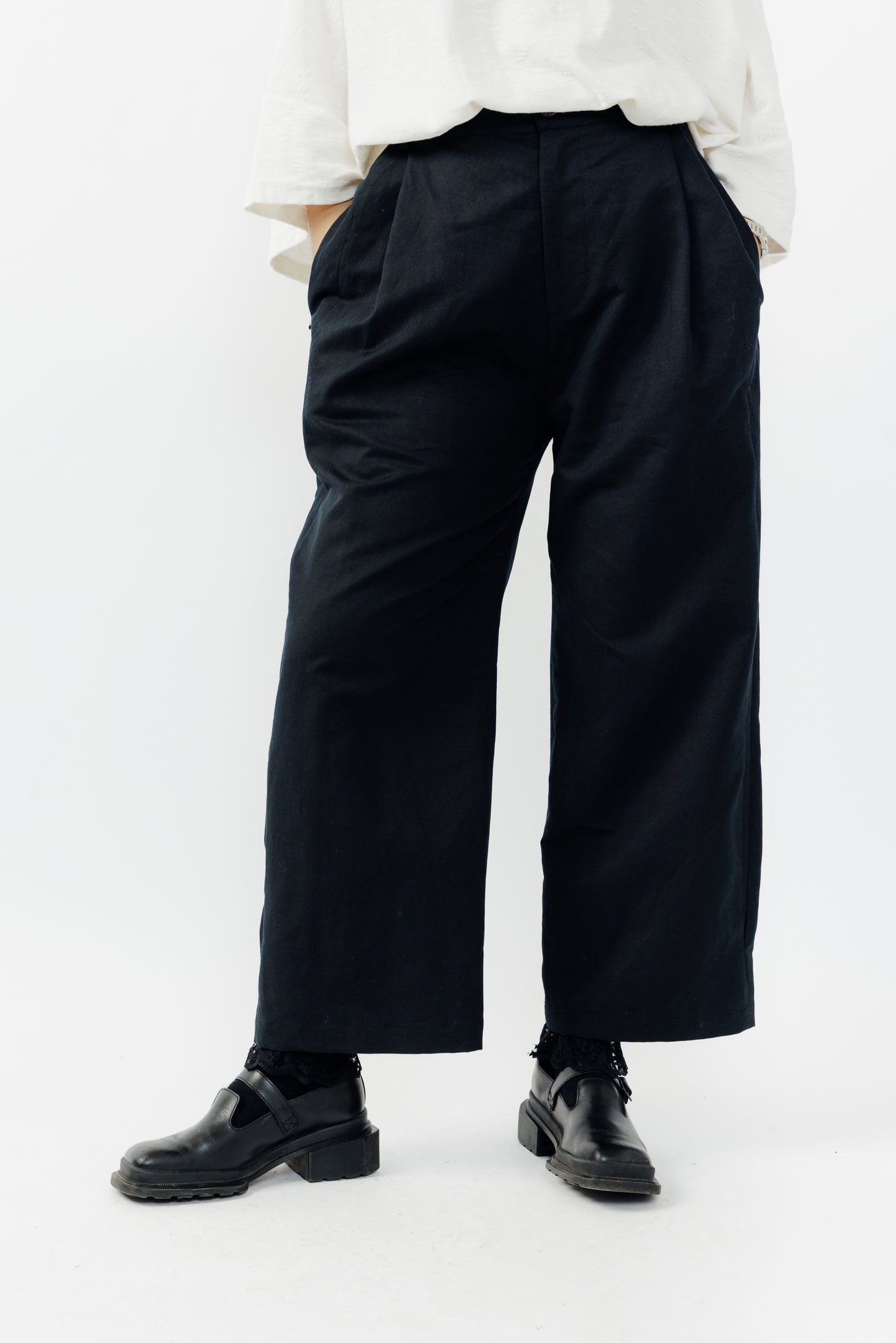 Pantalon droit de la marque Aïdama, coupe ample en coton et lin noir avec sangles ajustables à la taille. Porté par une mannequin femme et vu de face zoomé sur les jambes.