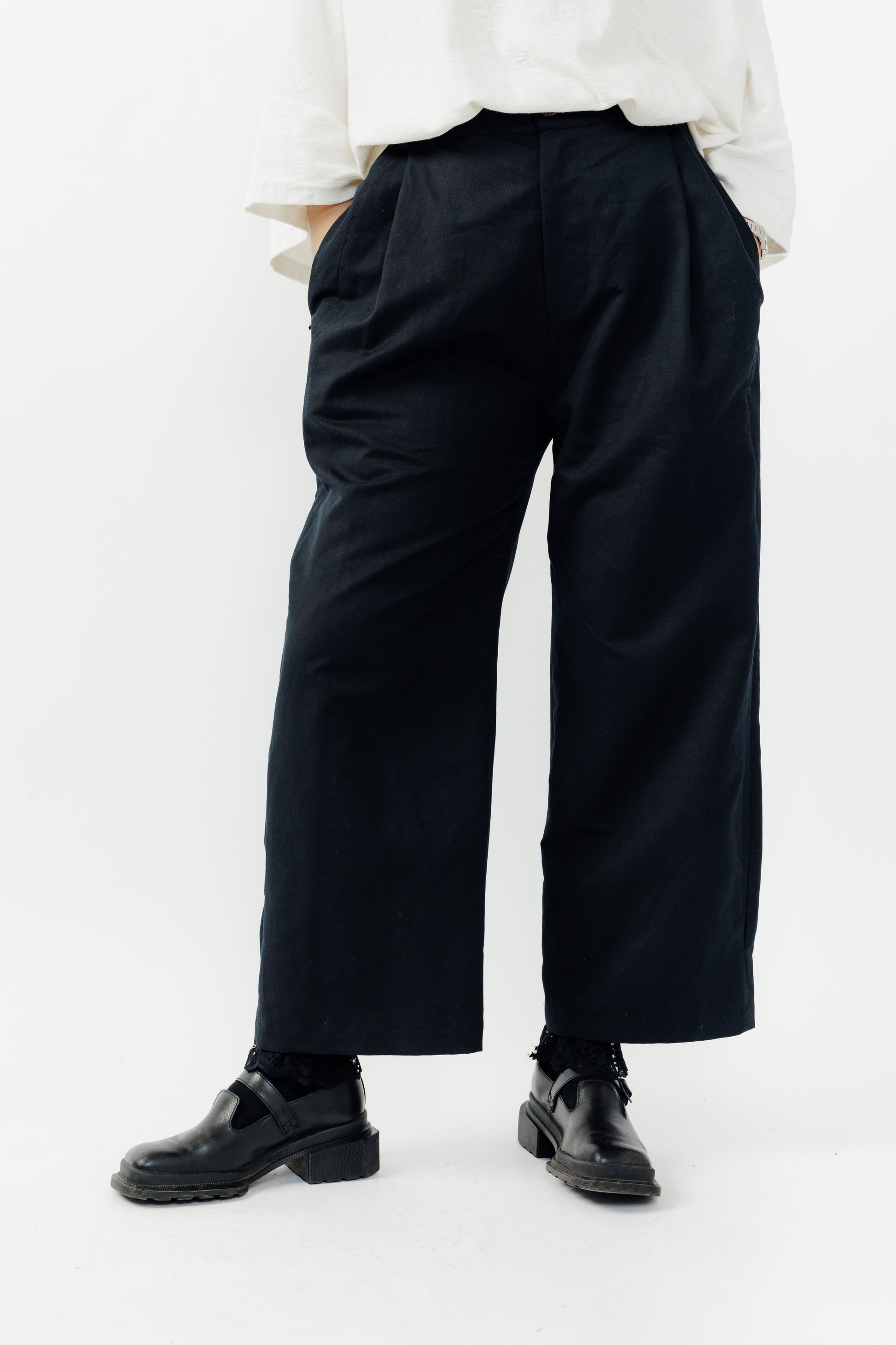 Pantalon droit de la marque Aïdama, coupe ample en coton et lin noir avec sangles ajustables à la taille. Porté par une mannequin femme et vu de face zoomé sur les jambes.