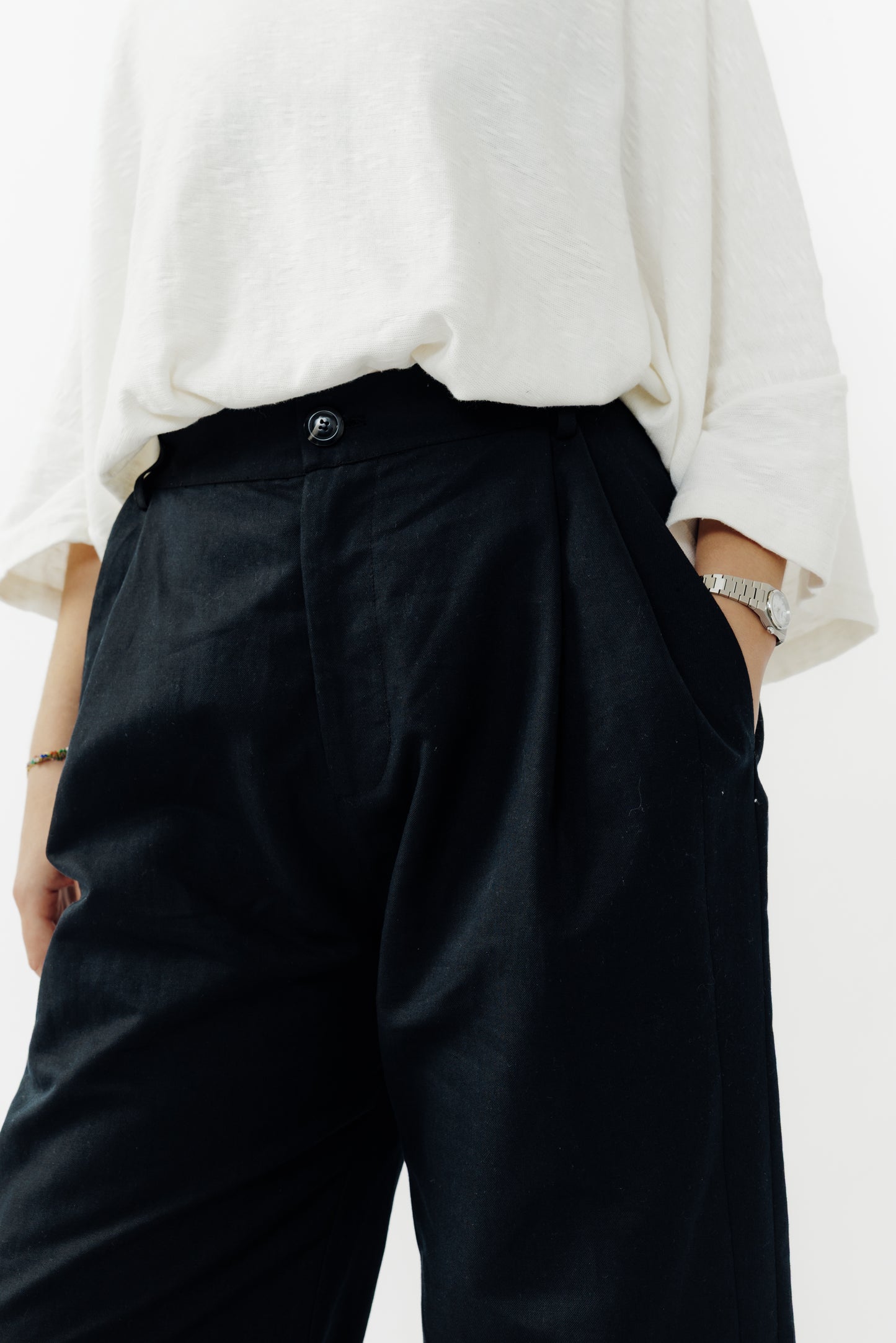 Pantalon droit de la marque Aïdama, coupe ample en coton et lin noir avec sangles ajustables à la taille. Porté par une mannequin femme et vu de face zoomé sur la ceinture.